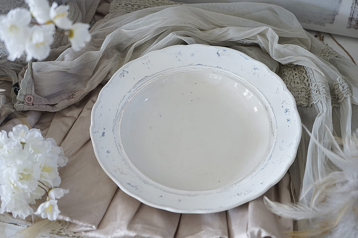 Rustikale, cremefarbene Schale auf einem gedeckten Tisch mit floralen Akzenten