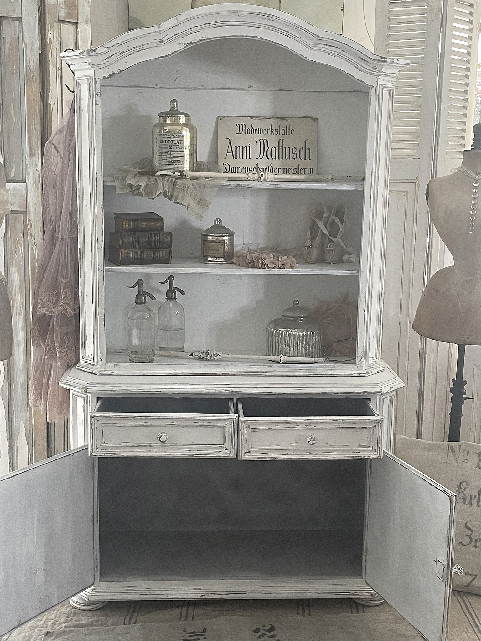 Antiker Vitrinenschrank mit nostalgischem Charme Vitrinenschrank mit Glaselementen, Büchern, und dekorativen Objekten im vintage Stil