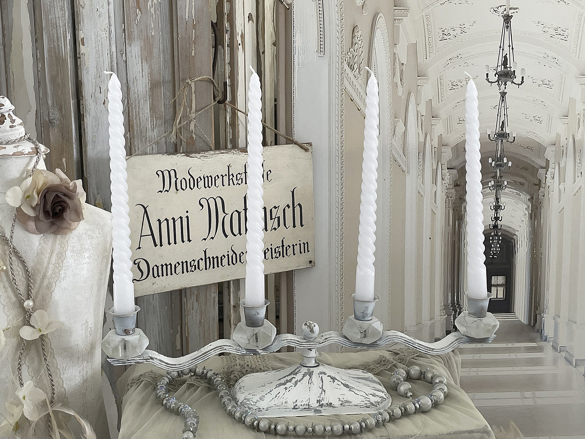 Eleganter Kerzenhalter mit weißen Kerzen und vintage Dekoration Kerzenhalter auf einem Tisch mit weißen Kerzen, einer Dekoration und einem Schild im Hintergrund.
