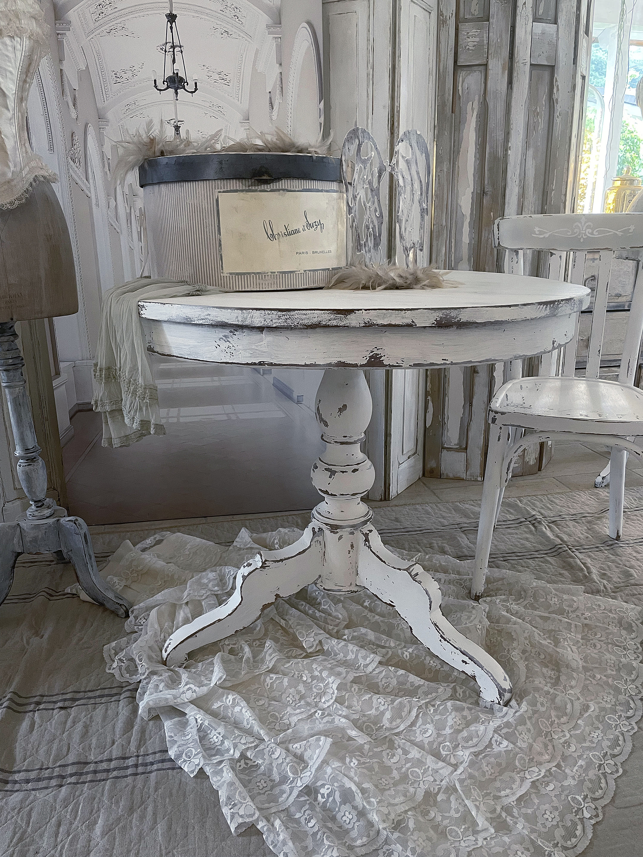 Eleganter runder Tisch im Shabby-Chic-Stil mit schicker weißen Tischdecke Runder, weißer Tisch im Shabby-Chic-Stil auf einer eleganten Tischdecke aus Spitze