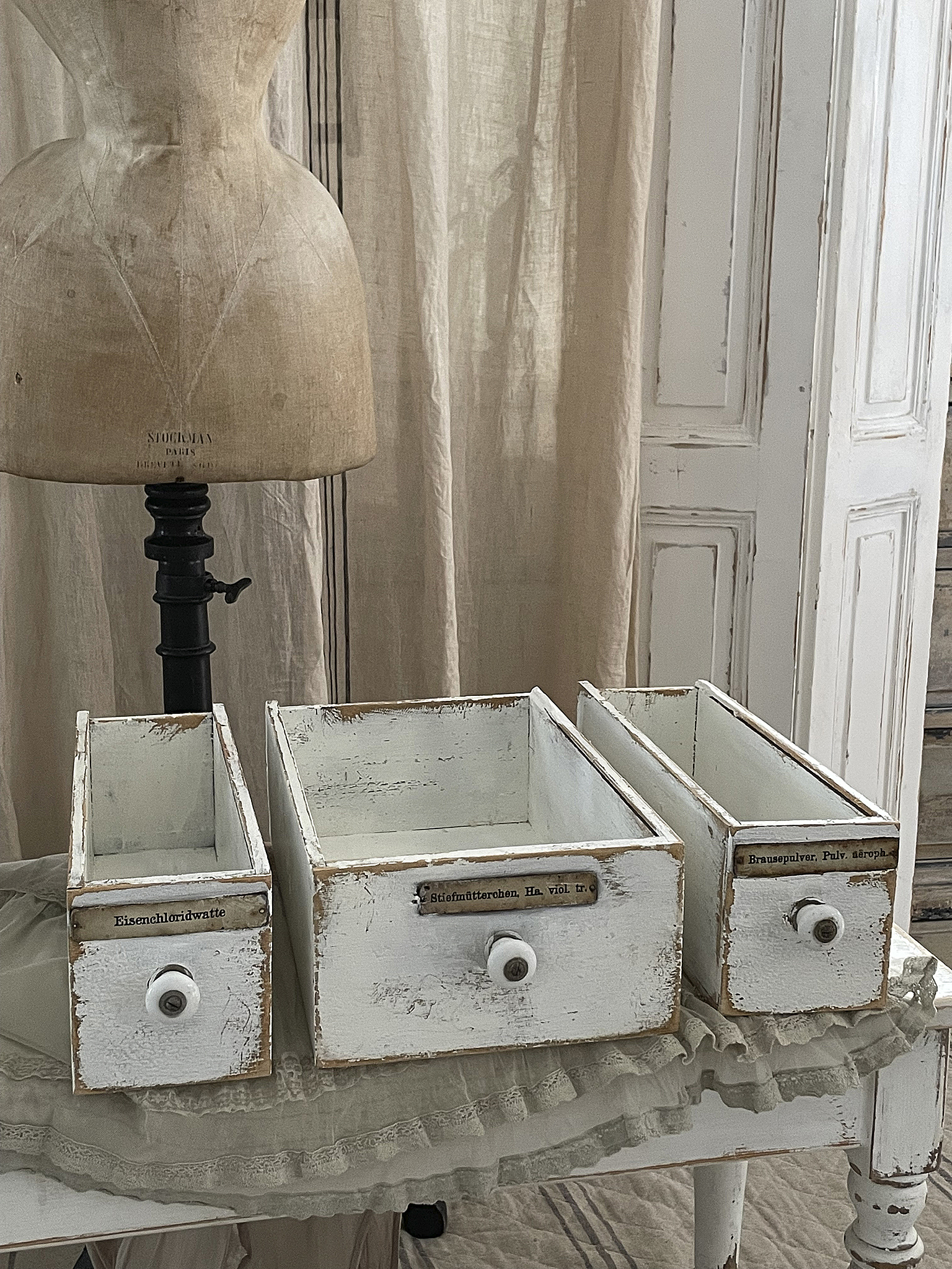 Drei vintage Holzboxen mit abgenutztem weißem Lack und Beschriftungen auf den Schubladen