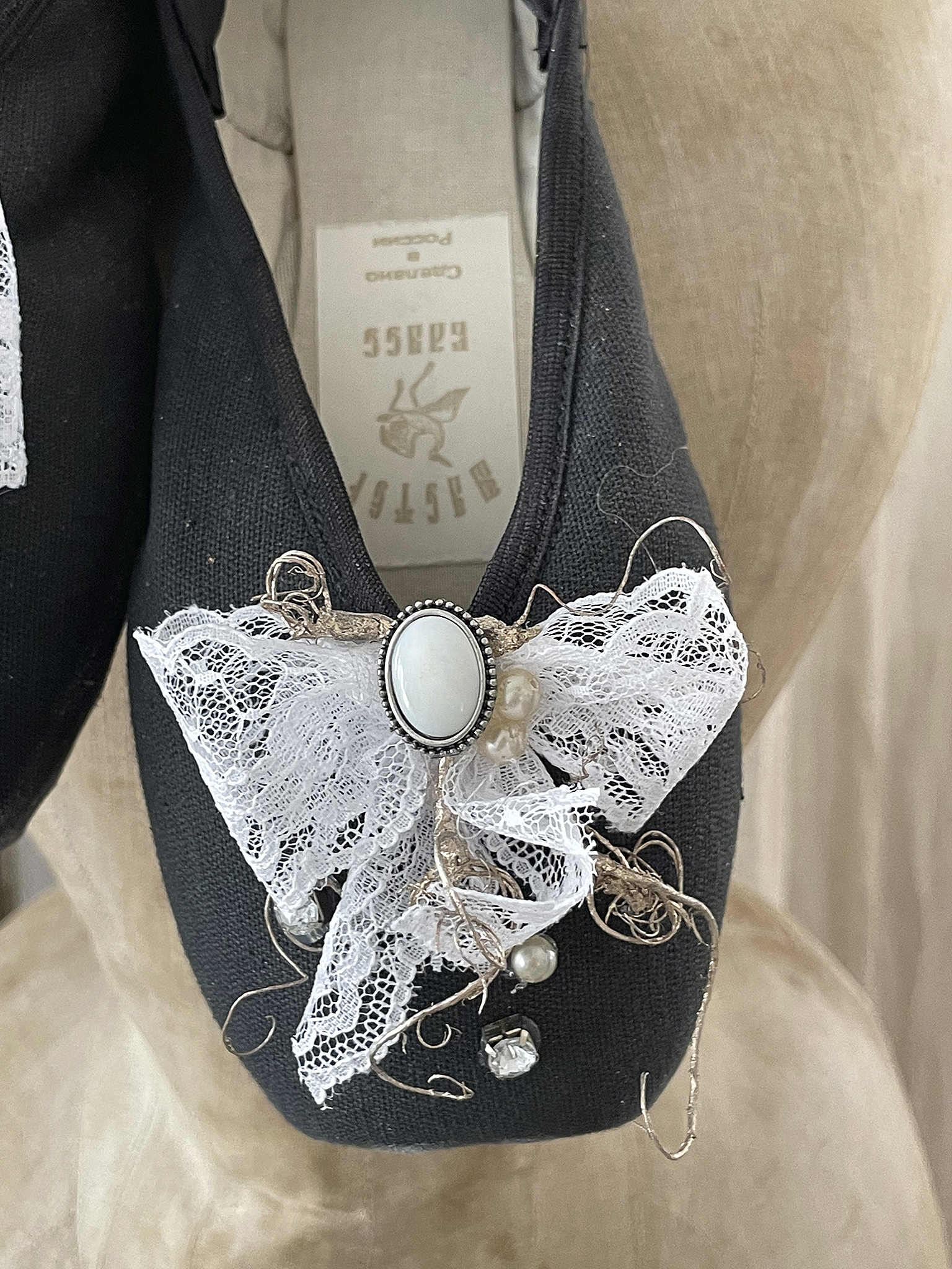 Elegante schwarze Ballerinas mit Spitze und Perlenverschluss Detailansicht von schwarzen Ballerinas mit einem dekorativen weißen Spitzenbogen und Perlen.
