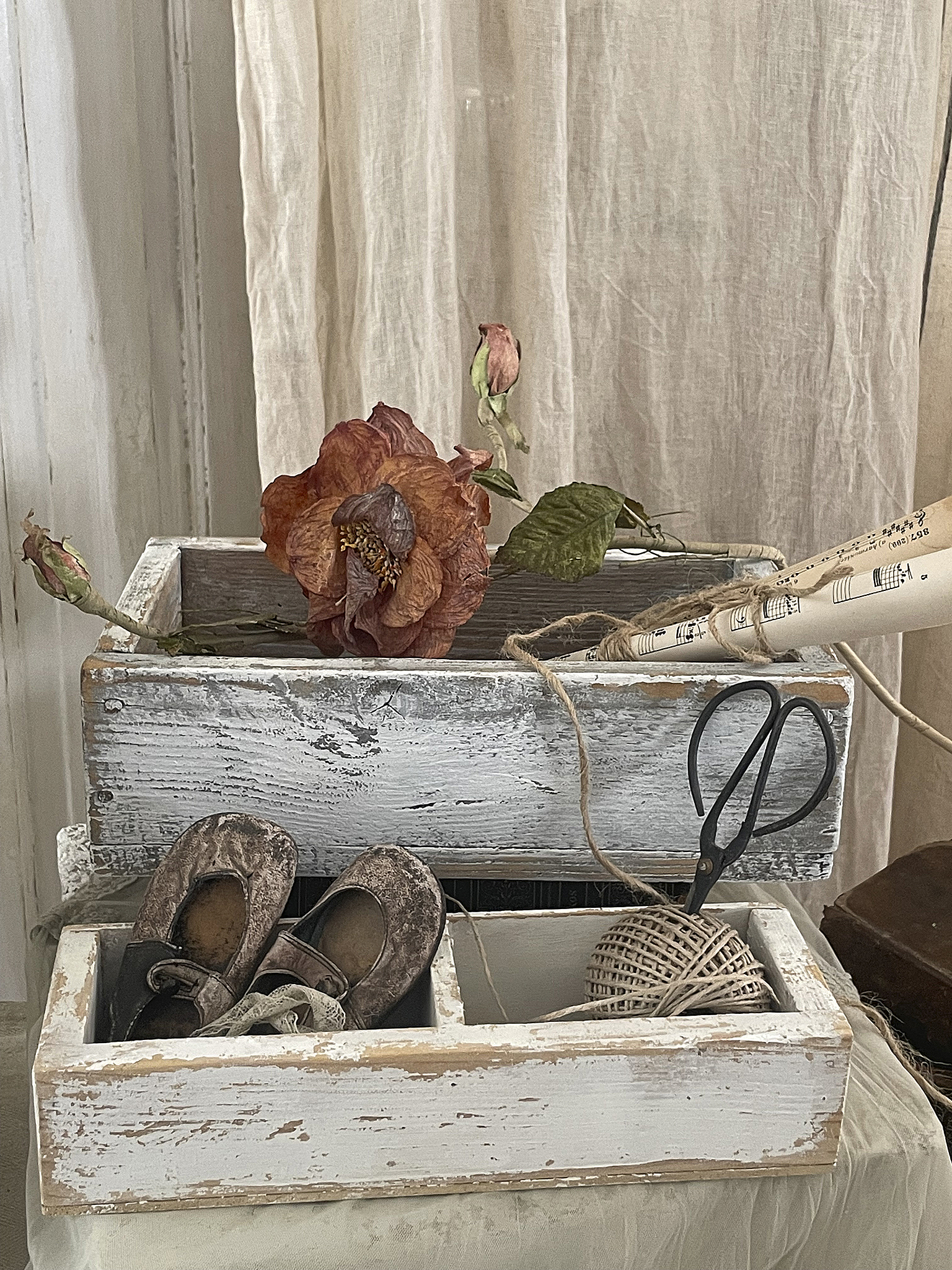 Dekorative Holzkisten mit floralen Elementen und alten Schuhen Holzkisten mit einer Blume, alten Schuhen, einer Schere und Schnur.