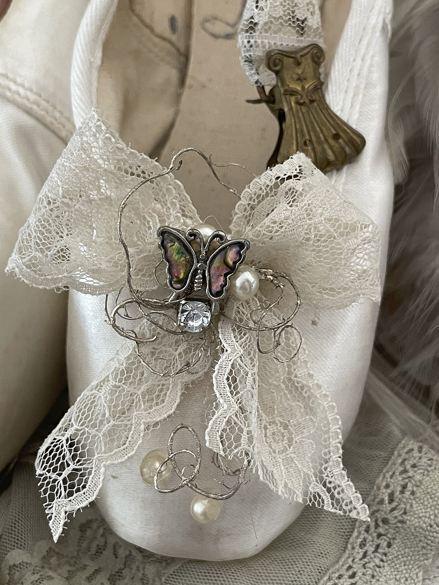 Elegante Ballettschuhe mit dekorativer Schleife und Schmetterling Nahaufnahme von weißen Ballettschuhen mit einer zarten Spitze und einer Dekoration in Form eines Schmetterlings