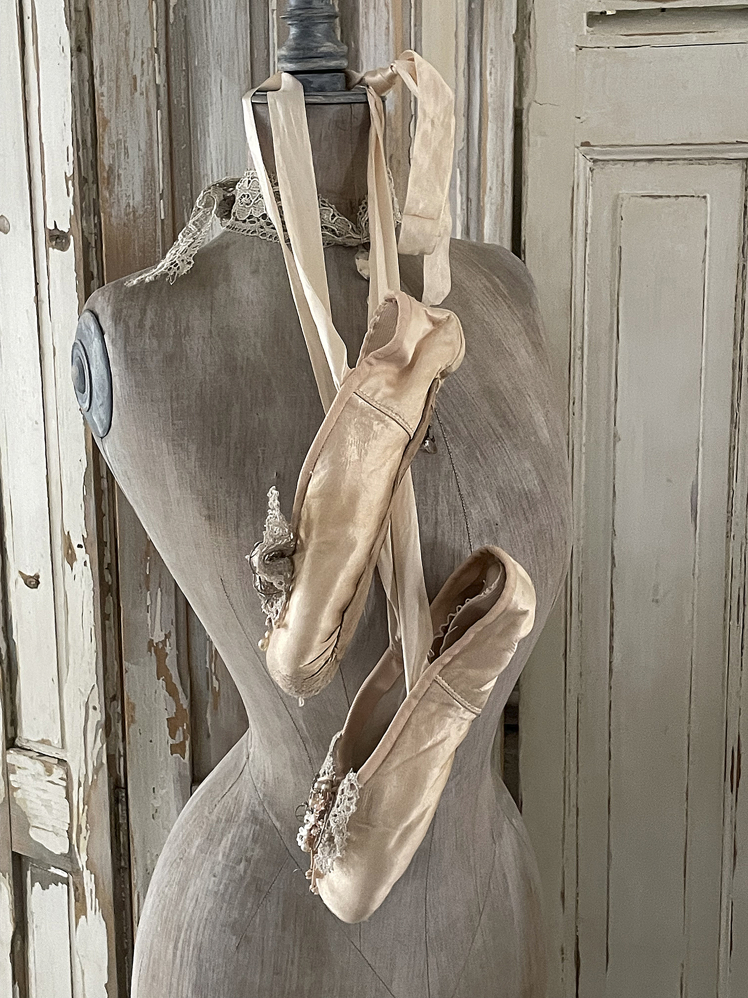 Elegante Ballettschuhe auf einer Schneiderpuppe Zwei stilvolle Ballettschuhe, sanft an einer Schneiderpuppe aufgehängt, mit zarten Riemen und Details.