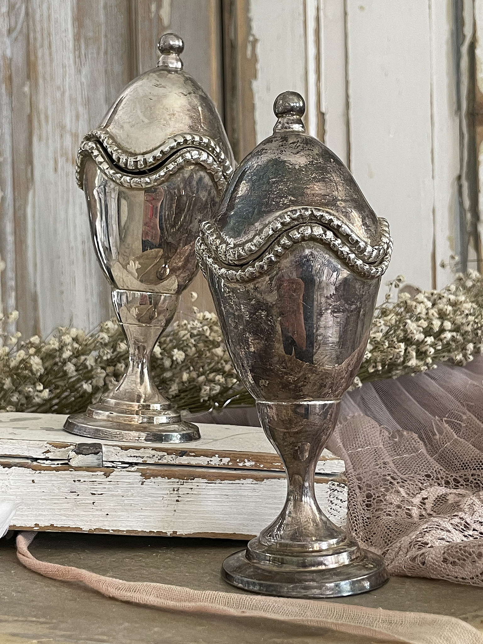 Elegante silberne Vintage-Dekoobjekte Zwei silberne Vintage-Dekorationsbehälter auf einem rustikalen Tisch