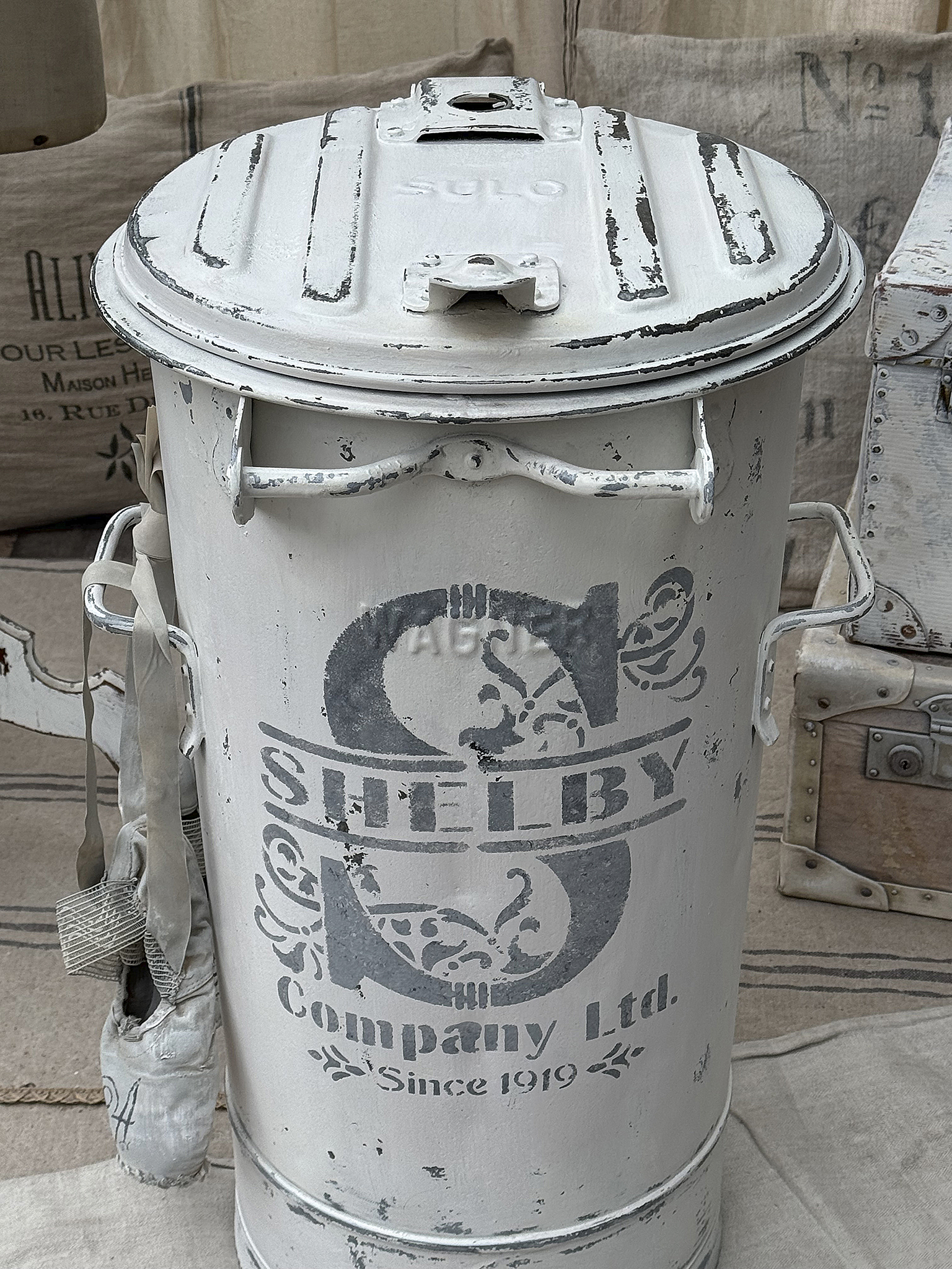 Vintage Abfalleimer mit SULO-Deckel und Shelby Company Ltd. Design Weißer, vintage Abfalleimer mit SULO-Deckel und bedrucktem Shelby Company Ltd. Logo, stilvolles Wohnaccessoire.