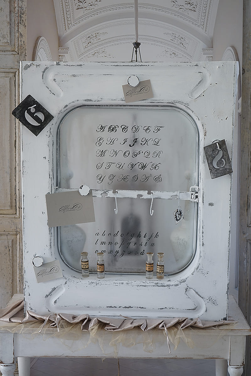 Eine weiße Wandtafel mit künstlerischen Schriftzügen und kleinen, beschrifteten Fläschchen