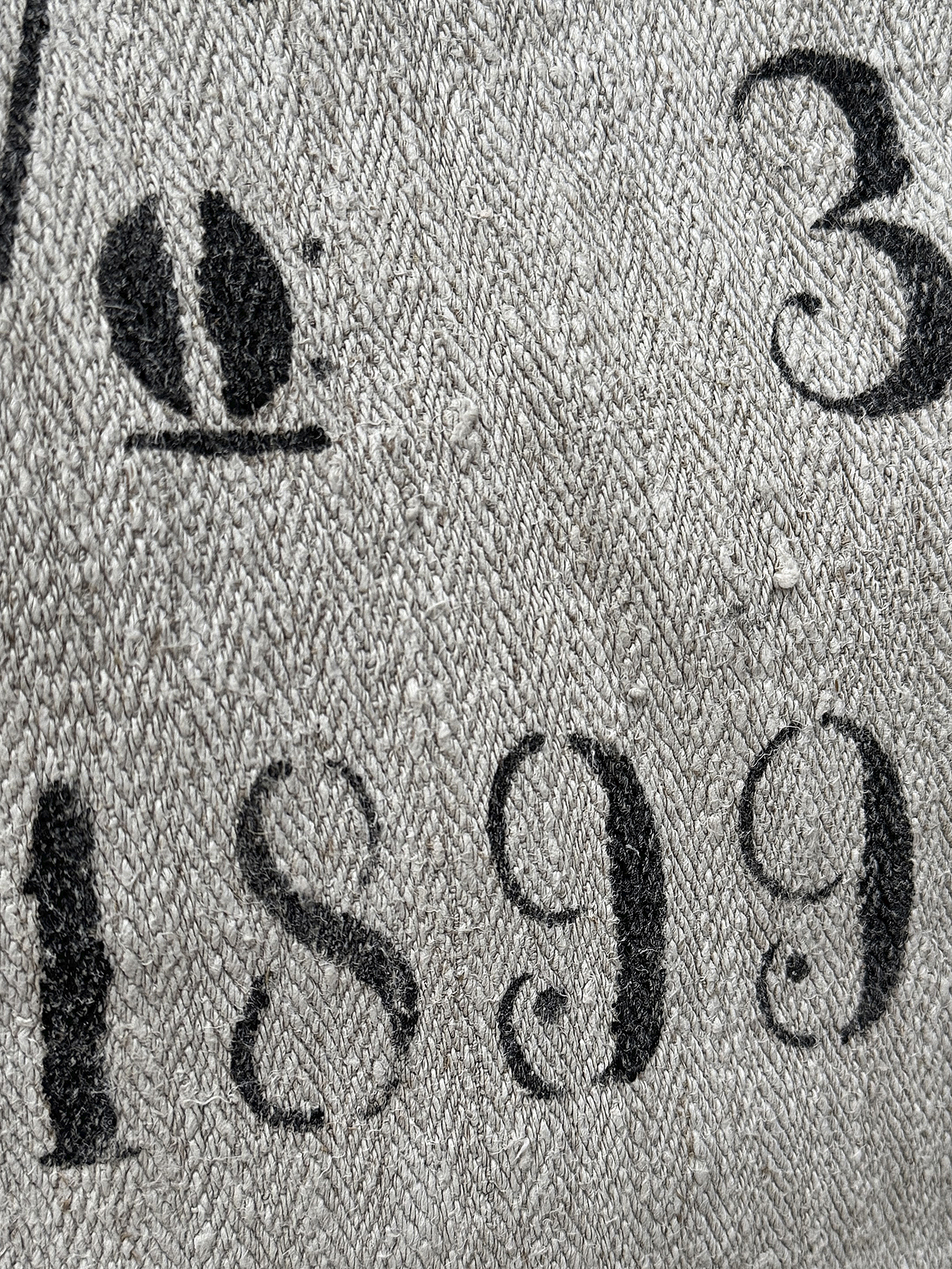 Nahaufnahme eines Stoffes mit Druck, auf dem die Zahlen 3 und 1899 zu sehen sind.