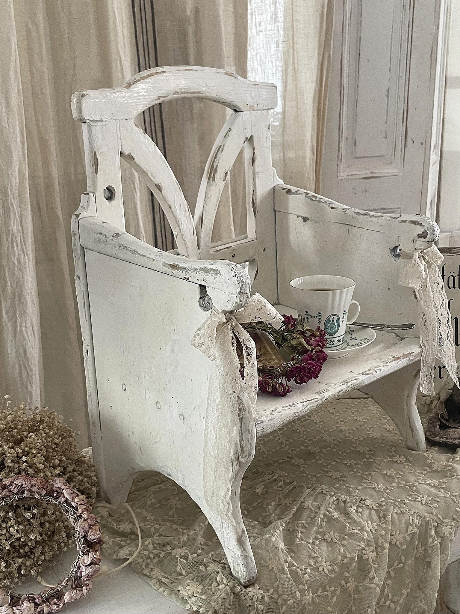 Weißer Holztisch im Vintage-Stil, dekoriert mit einer Tasse und getrockneten Blumen