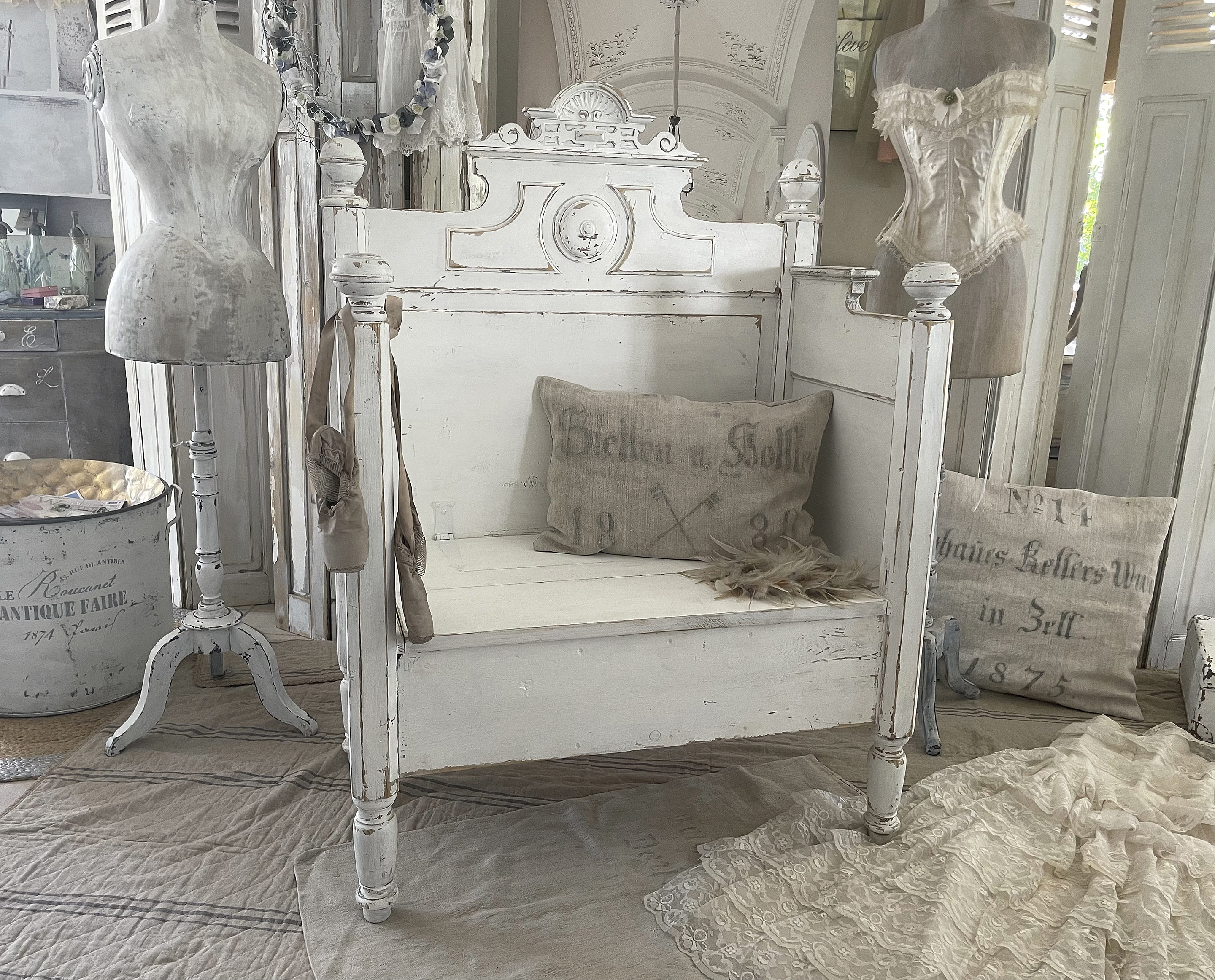 Dekorative antike Holzbank im Landhausstil mit Kissen und Mannequin, umgeben von nostalgischen Accessoires