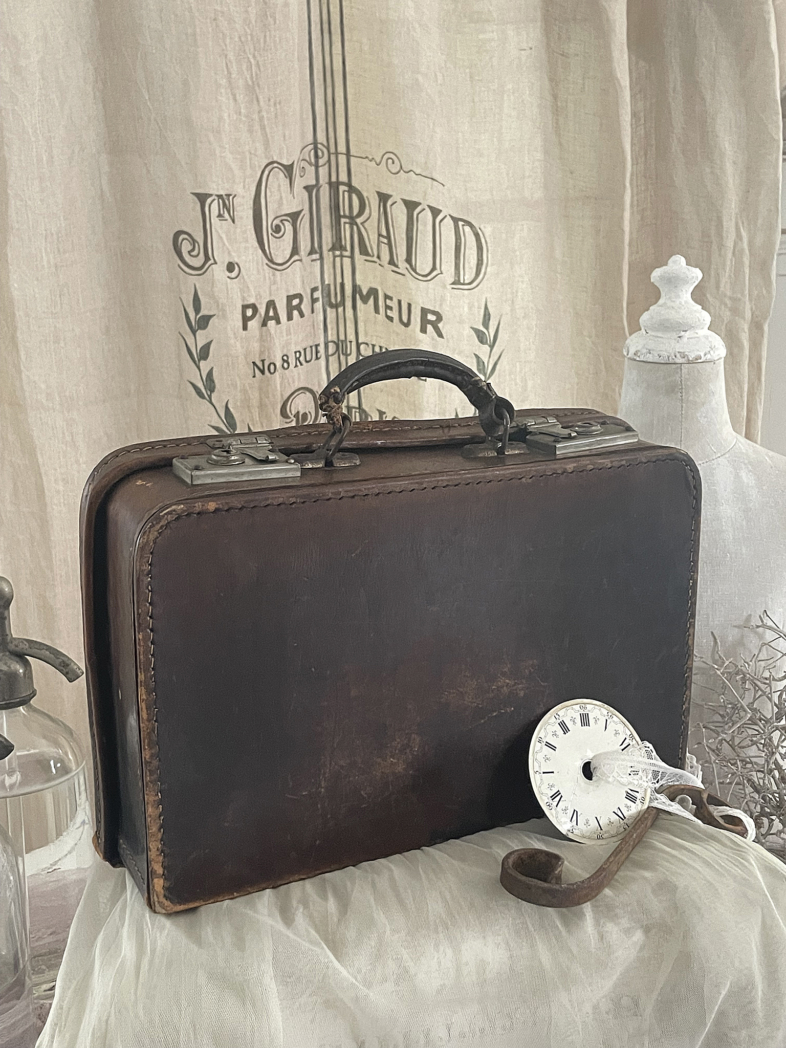 Vintage Lederkoffer mit nostalgischem Uhrzeiger und Dekor Alter Lederkoffer mit Uhr und antikem Zubehör auf einem Tisch