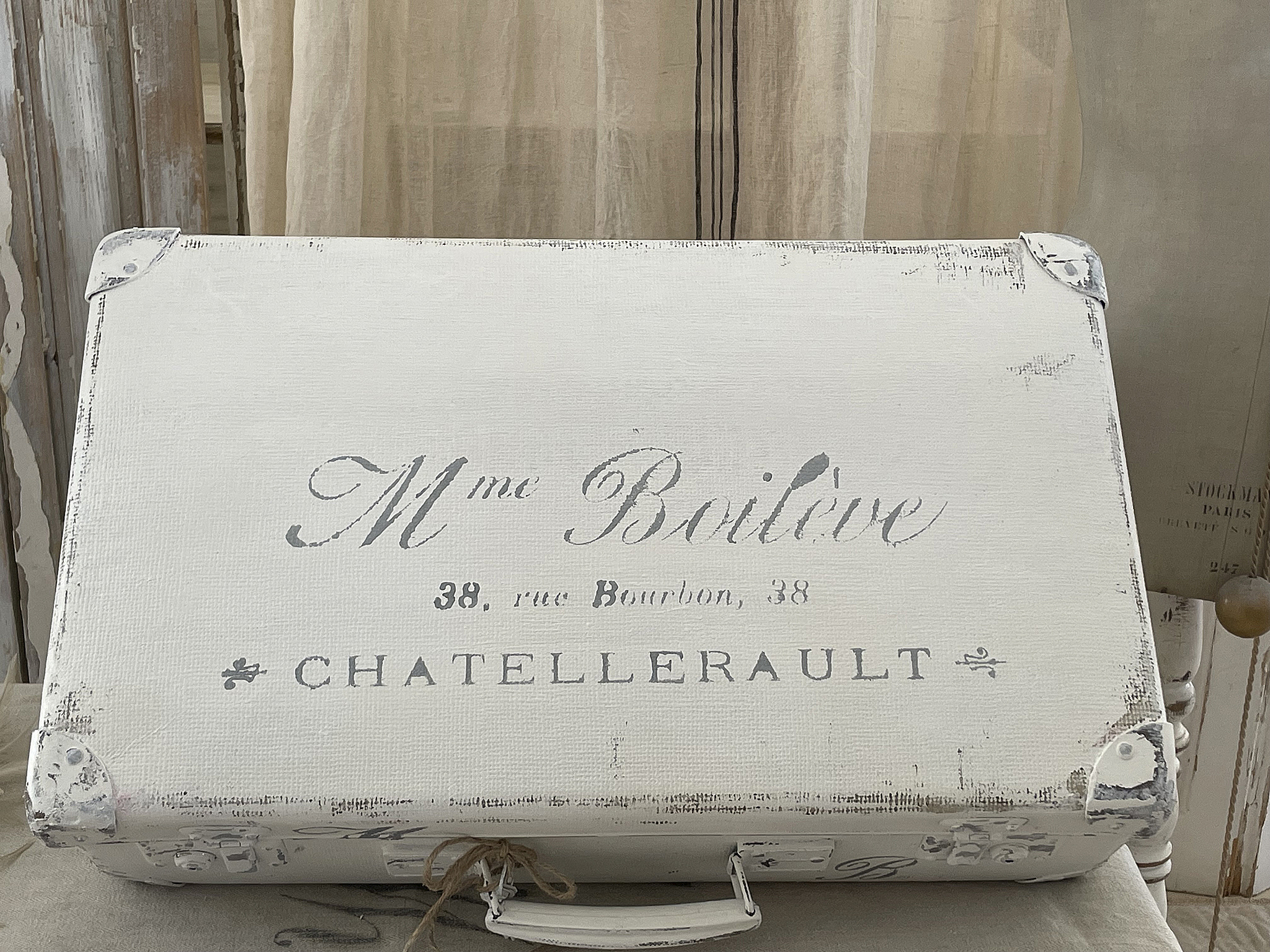 Vintage Koffer mit französischer Aufschrift und nostalgischem Design Ein nostalgischer, weißer Koffer mit der Beschriftung 'M me Baillève' und der Adresse '38, rue Bourbon, 38' in einem vintage Stil.
