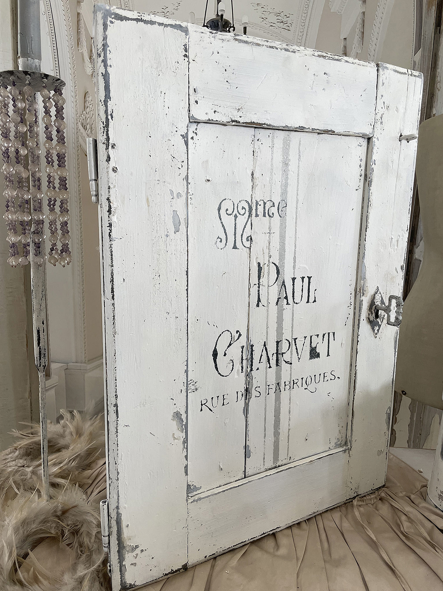 Detailaufnahme einer antiken Holzschranktür mit Schriftzug Paul Charvet und dekorativen Elementen.