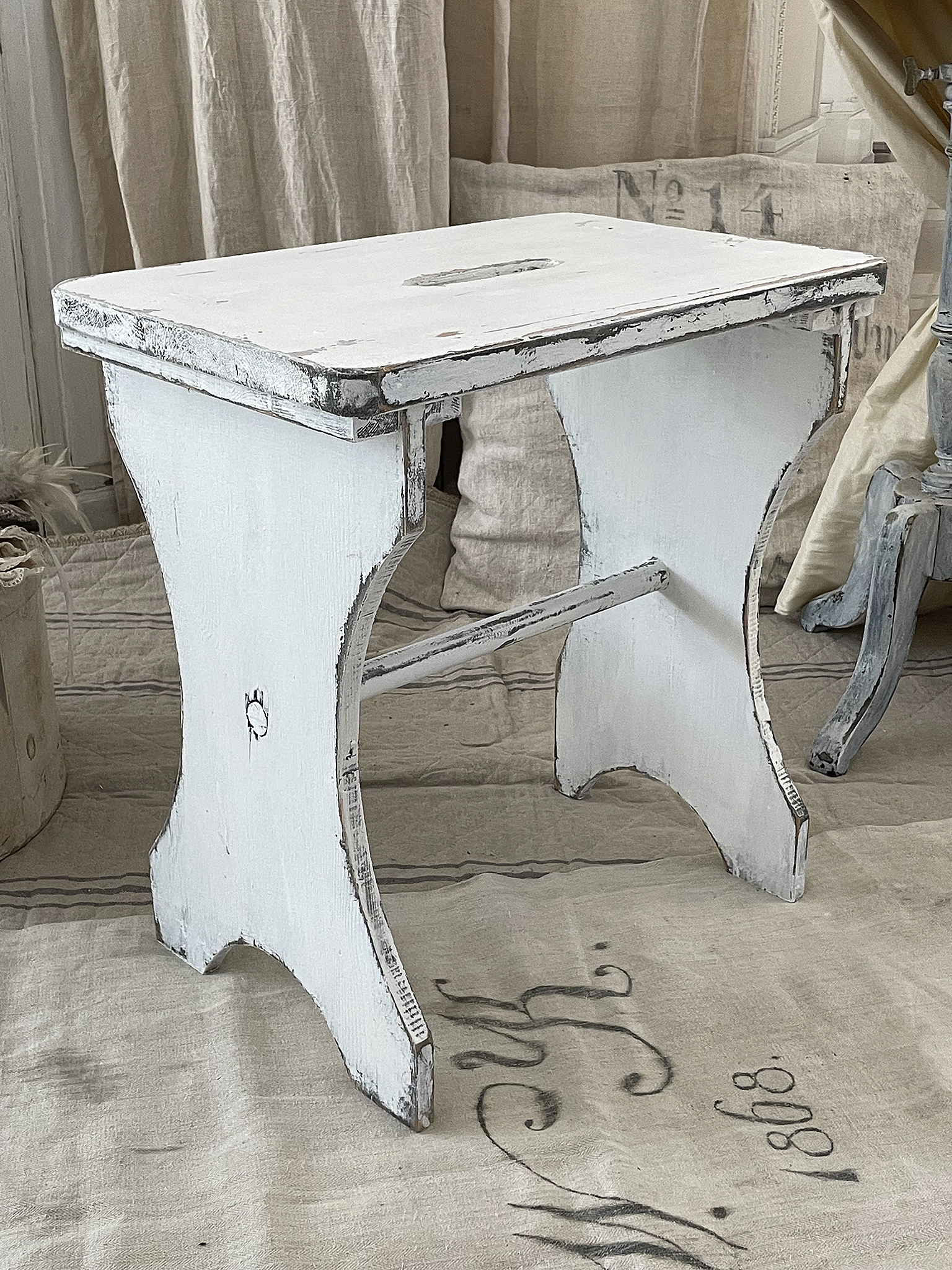 Antiker weißer Hocker mit abgenutzter Oberfläche Ein antiker Hocker in Weiß mit charmanten Gebrauchsspuren, ideal für nostalgische Räume.