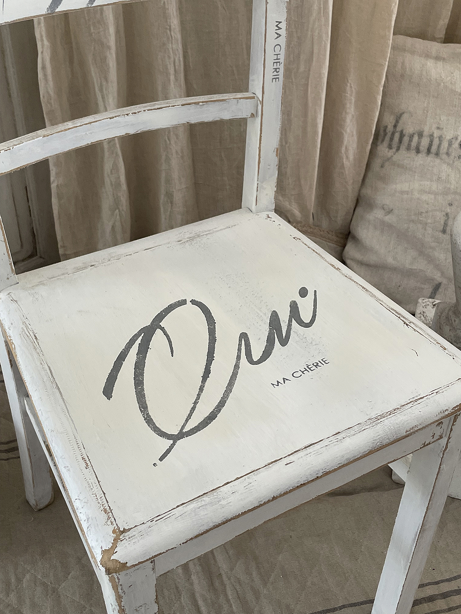 Dekorativer Stuhl mit französischem Schriftzug 'Oui' und shabby-chic Design Stuhl im shabby-chic Stil mit dem Schriftzug 'Oui' und 'MA CHÉRIE' auf der Sitzfläche.