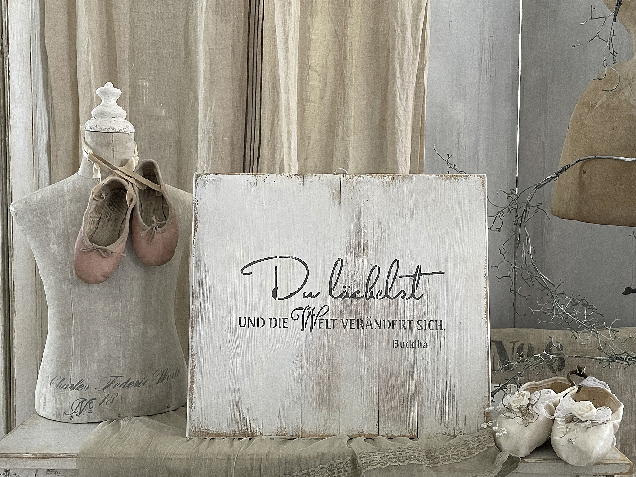 Kunstwerk mit der Aufschrift 'Du liebst und die Welt verändert sich.' neben Ballettschuhen und fröhlicher Deko.
