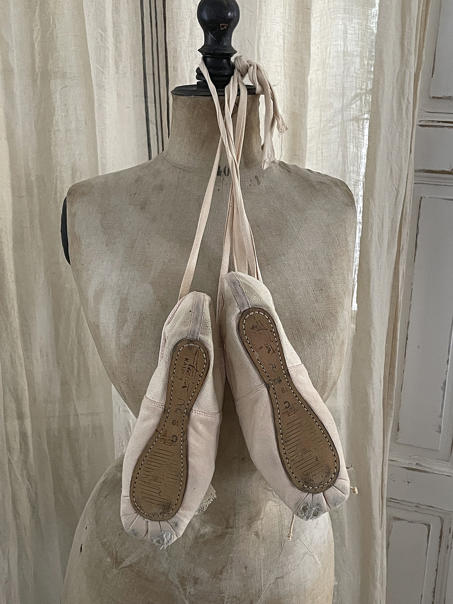 Elegante Ballettschuhe an einer Schneiderpuppe Ballettschuhe aus Stoff hängen an einer Schneiderpuppe, zeigen die Sohle und das saubere Design.