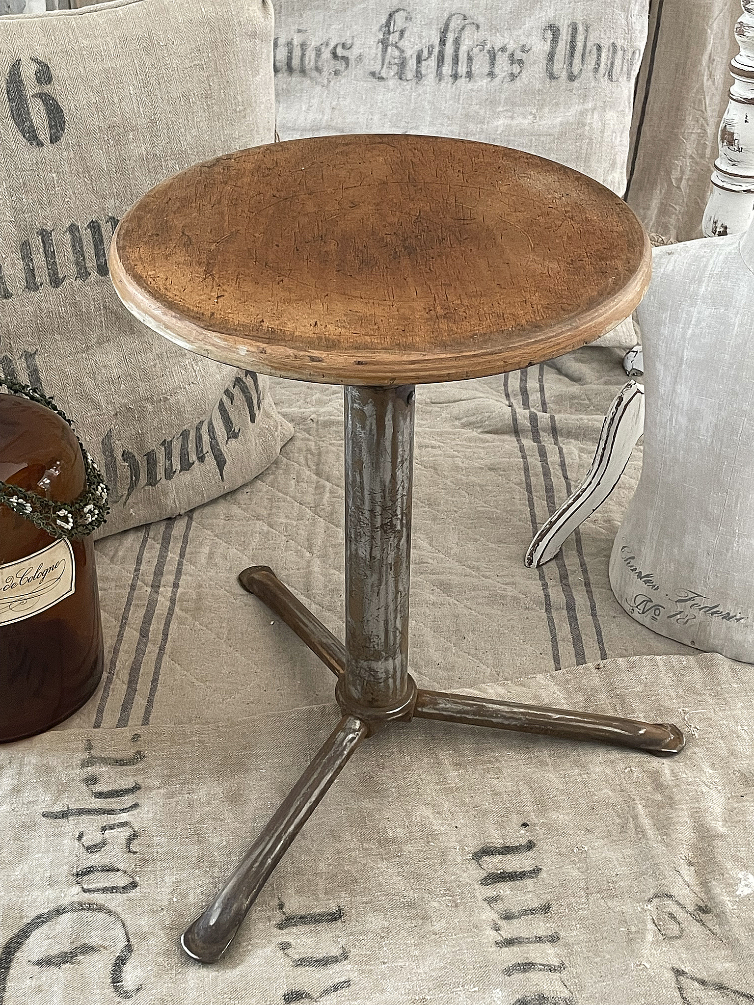 Holzhocker mit rundem Sitz und stabilem Metallgestell auf Stoffuntergrund