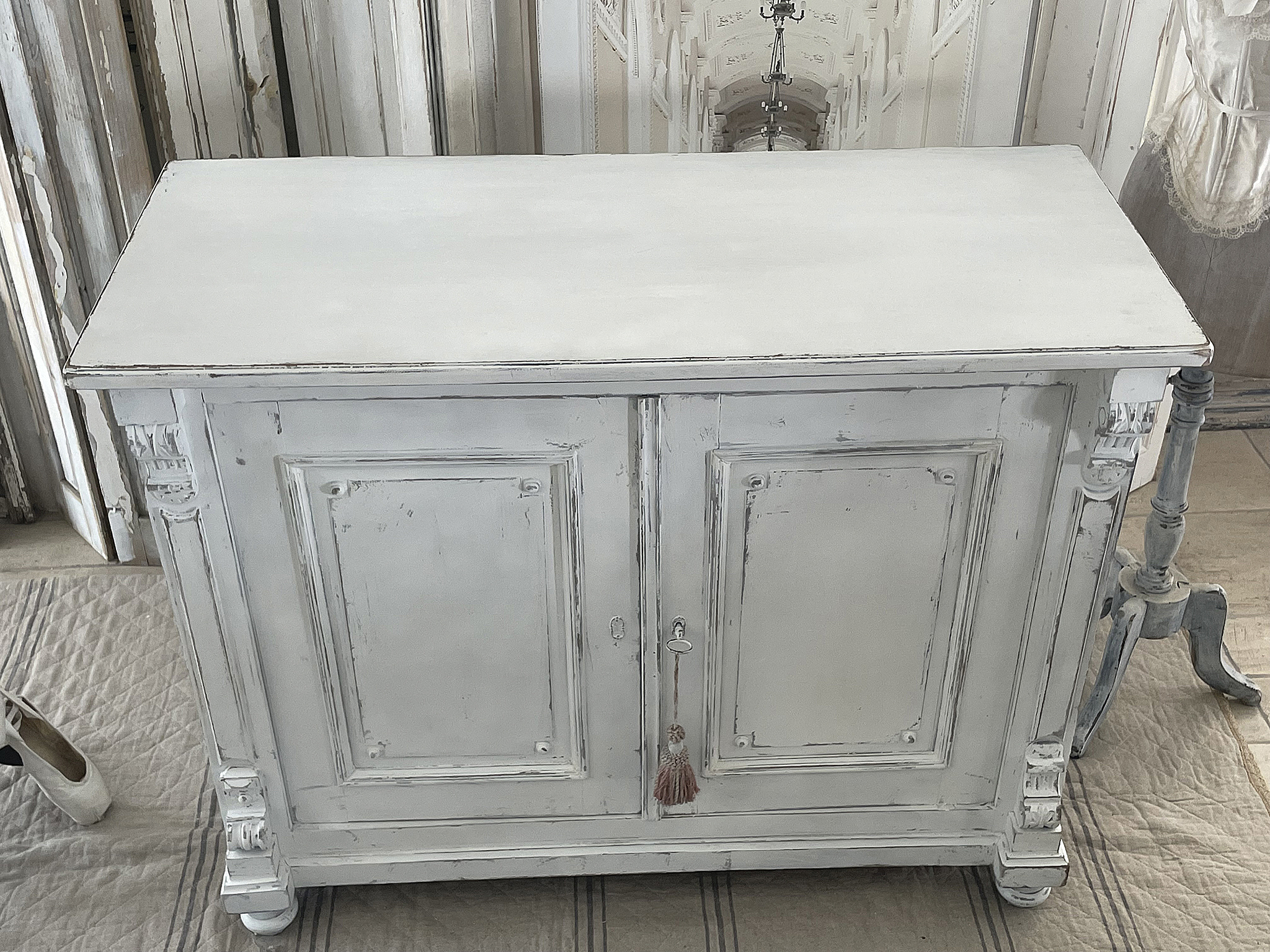 Antiker, weißer Sideboard mit aufwendiger Verzierungen Weißes Sideboard im antiken Stil mit zwei Türen und eleganten Details