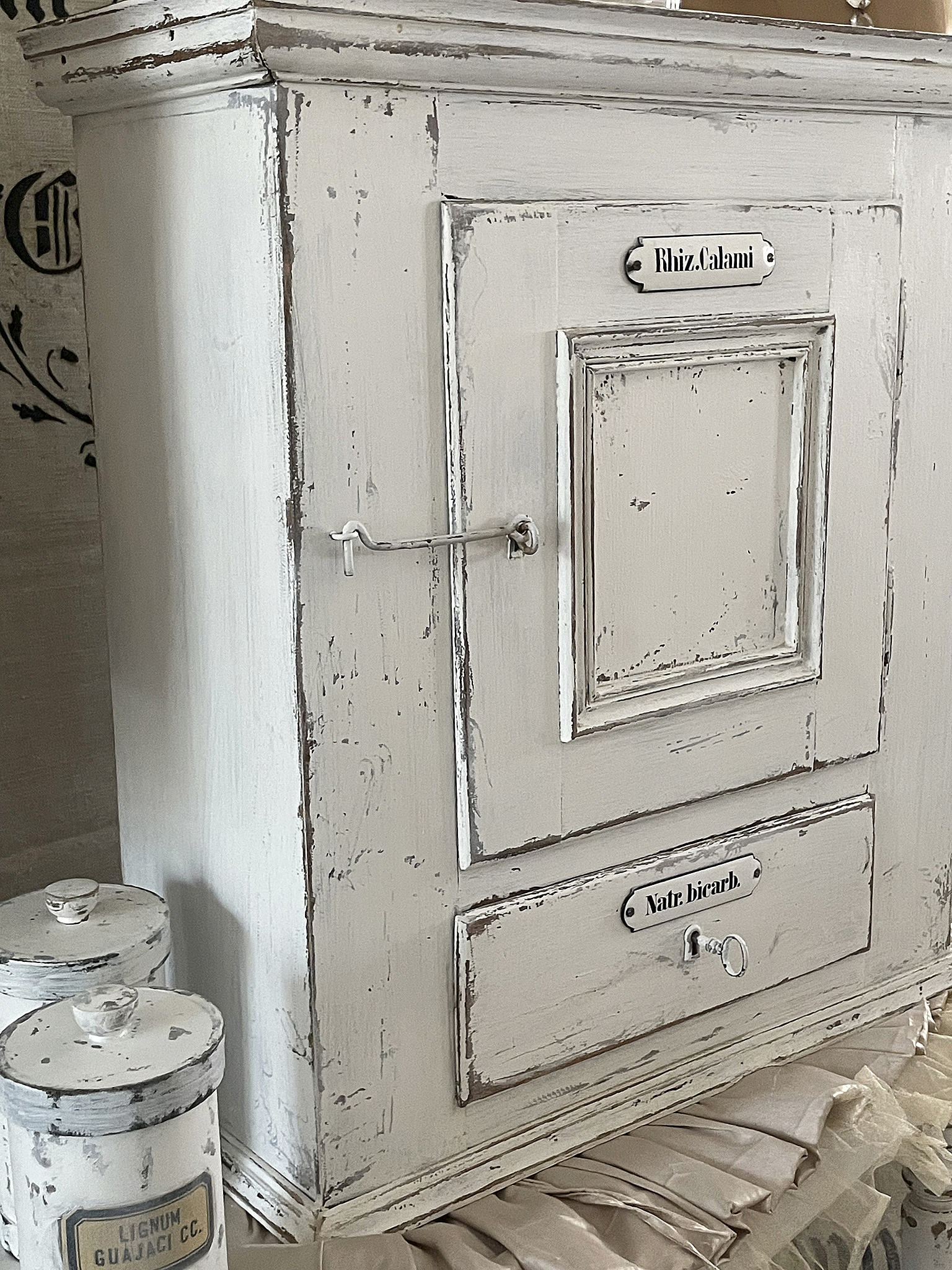 Antiker Holzschrank mit Beschriftungen und Vintage-Design Antiker Schrank in Weiß mit abgenutzter Oberfläche und Beschriftungen