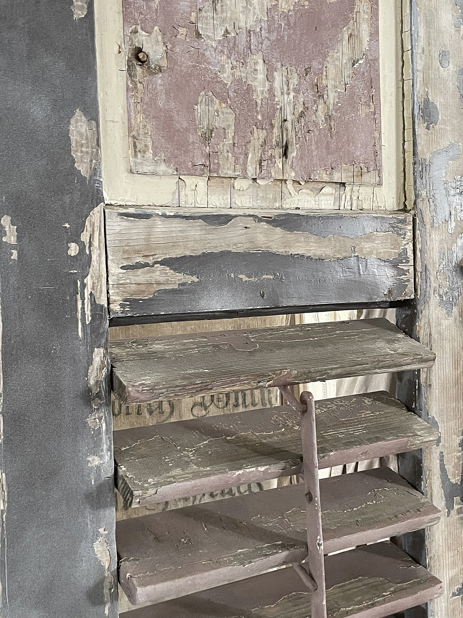 Detailansicht eines alten Holzregals mit abblätternder Farbe und verzierten Brettern