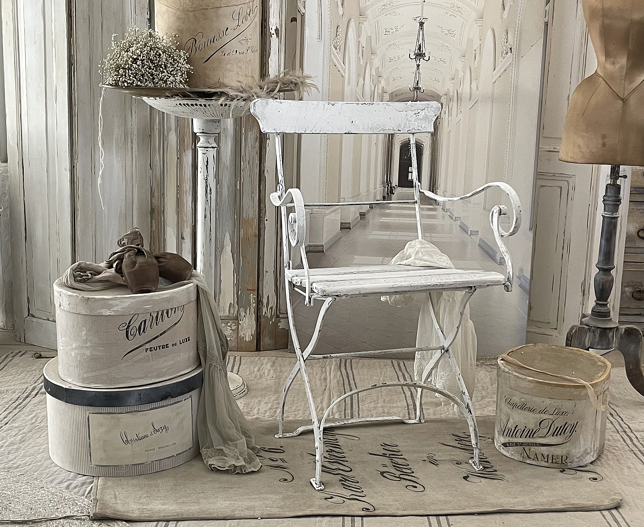 Vintage Weißer Stuhl mit dekorativen Kartons und Stoffen Ein weißer vintage Stuhl steht vor einer eleganten Kulisse mit stilvollen Kartons und Stoffen.