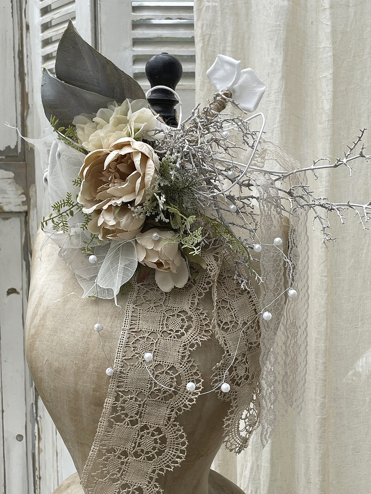 Detailaufnahme eines eleganten Blumenkranzes mit Spitze und Perlen auf einem Mannequin.
