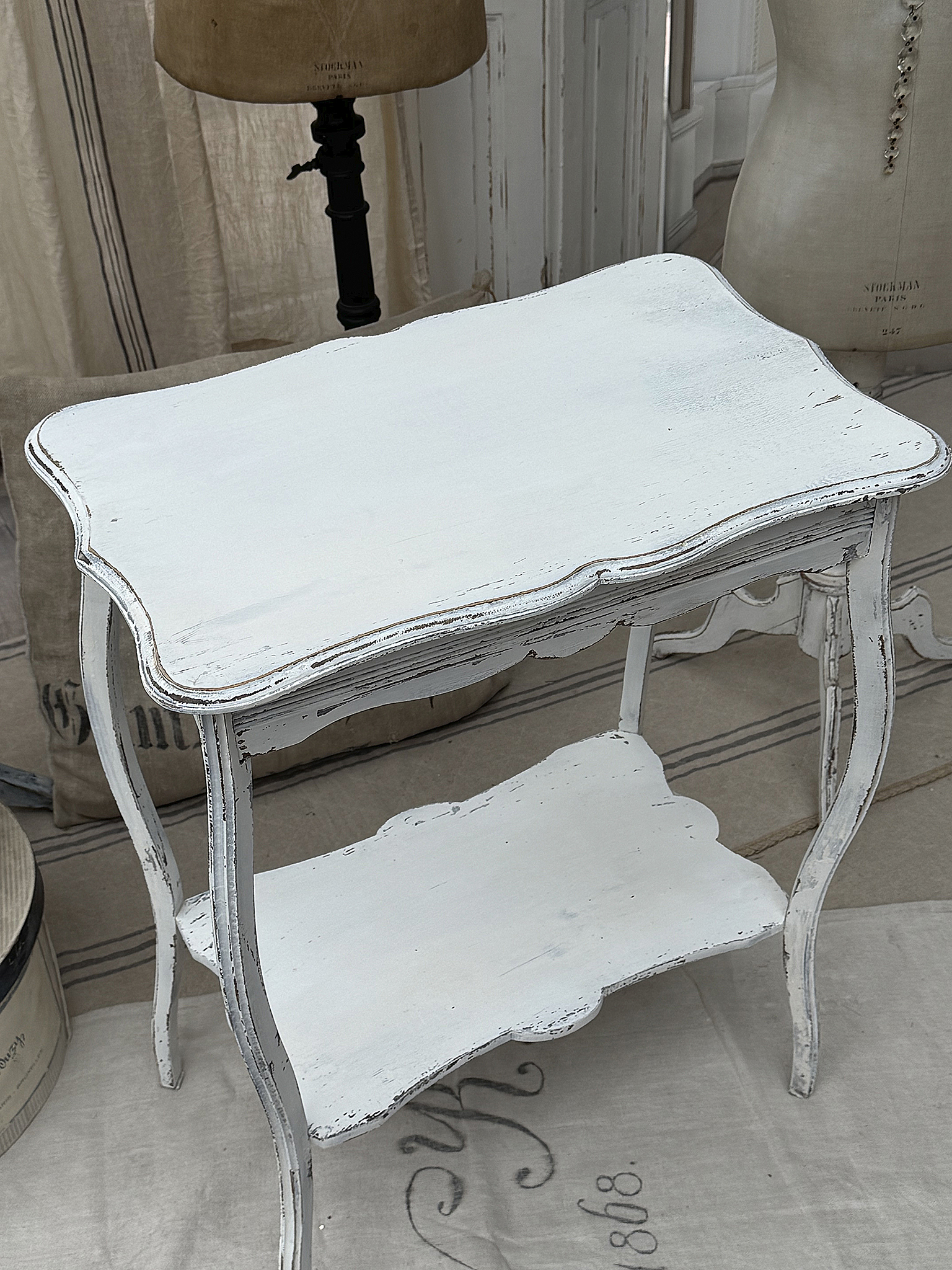 Eleganter weißer Beistelltisch mit antique Finishing Weißer Beistelltisch mit geschwungenen Linien und unterer Ablagefläche