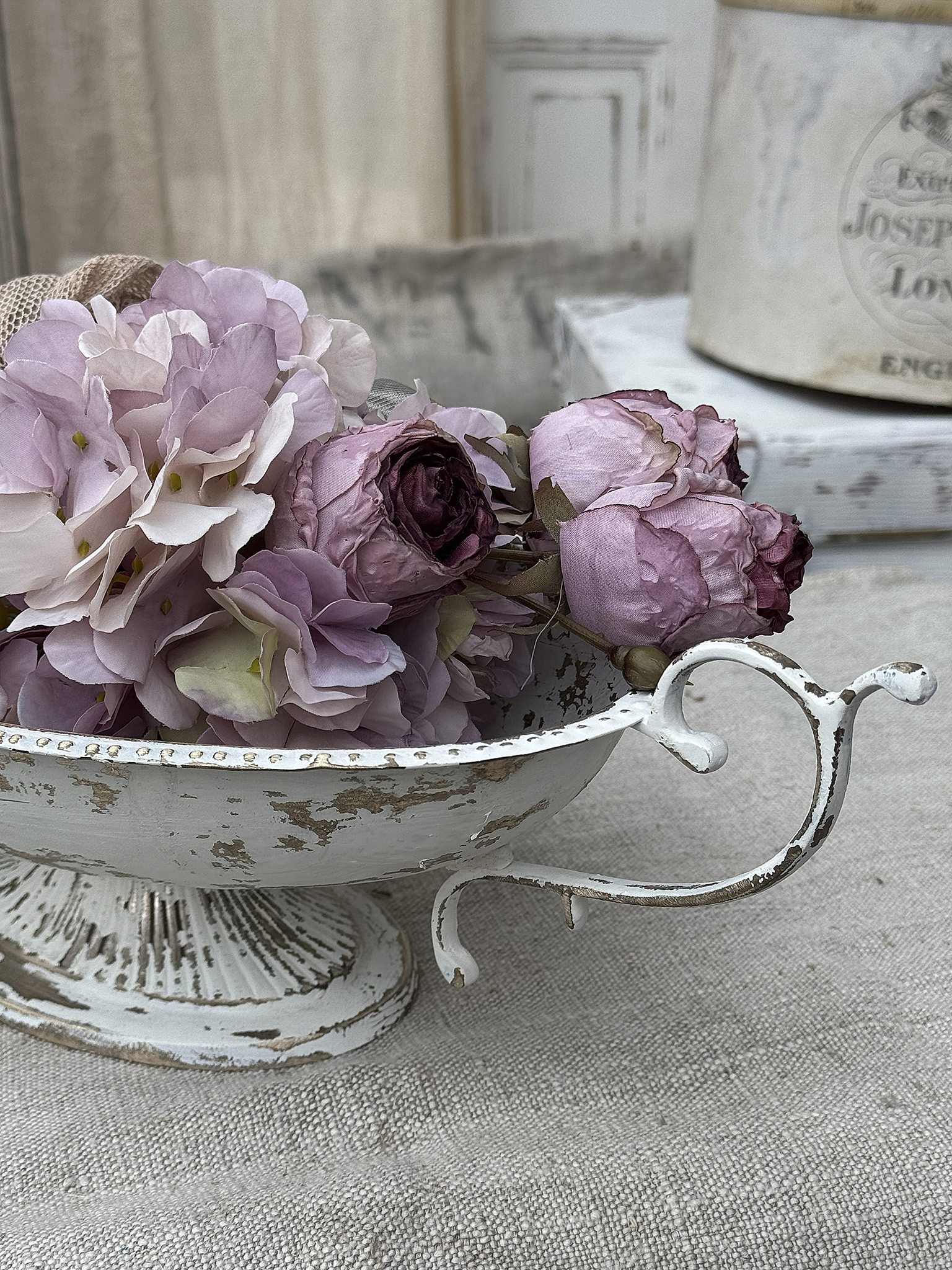 Schale mit kunstvollen, pastellfarbenen Blumenarrangement auf einem neutralsfarbigen Hintergrund