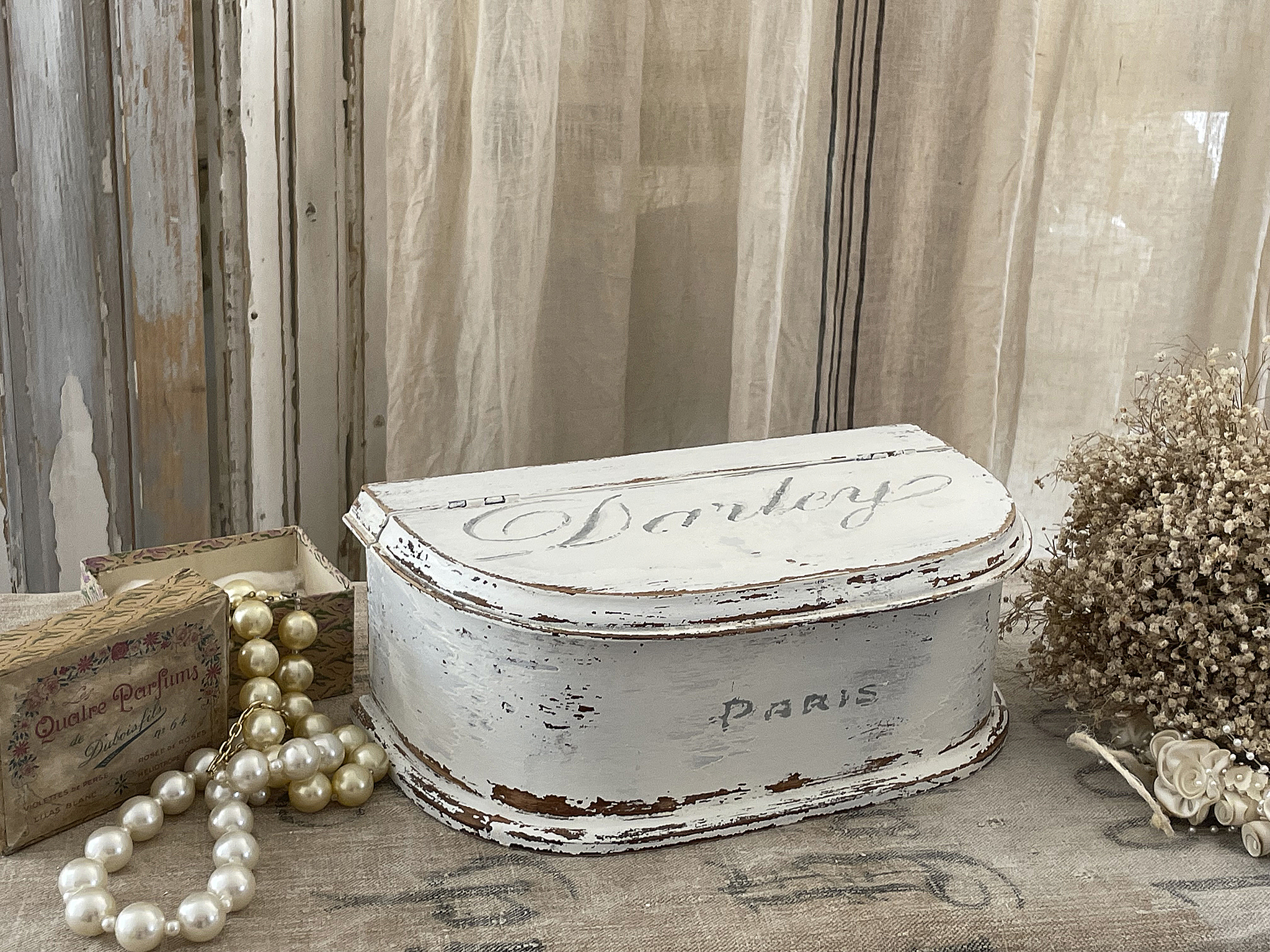 Antike Schmuckbox mit Blumenmuster und Perlen Hübsche Vintage Schmuckbox aus Holz, verziert mit Paris Schriftzug, umgeben von Perlen und Trockenblumen.