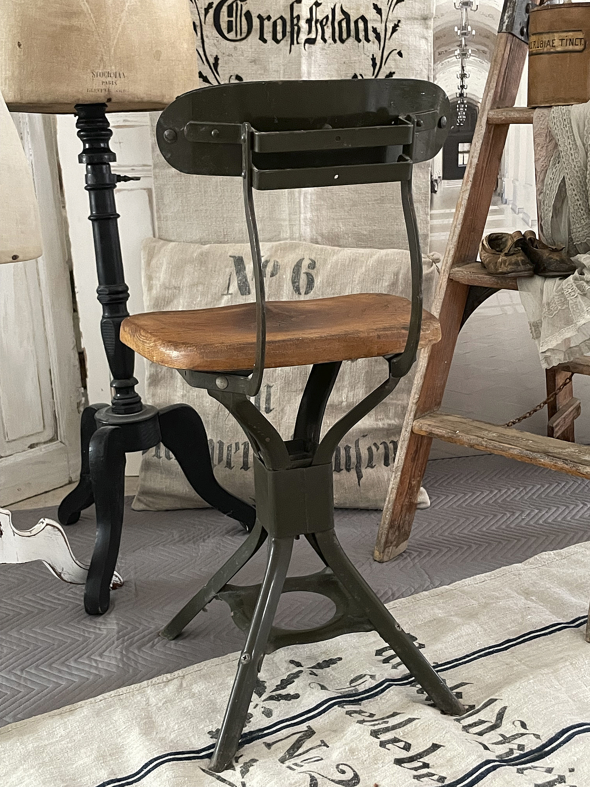 Stylischer Vintage-Hocker mit Holzsitz und grüner Metallbasis Vintage-Hocker mit Holzsitz, grünem Metalldesign und dekorativer Umgebung