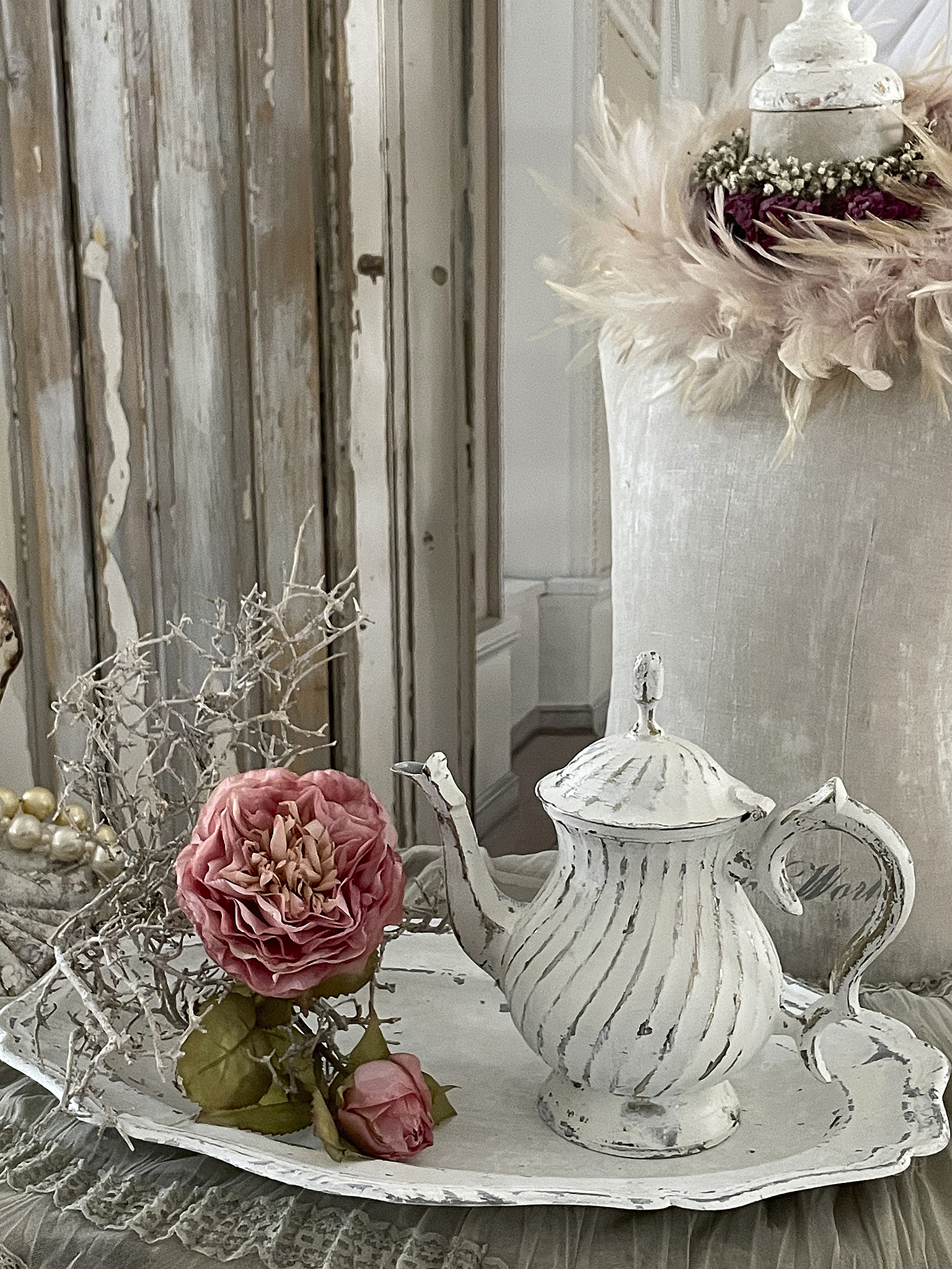 Dekorative Teekanne in Vintage-Stil mit rosa Rosen und Trockenblumen auf einem eleganten Tablett.