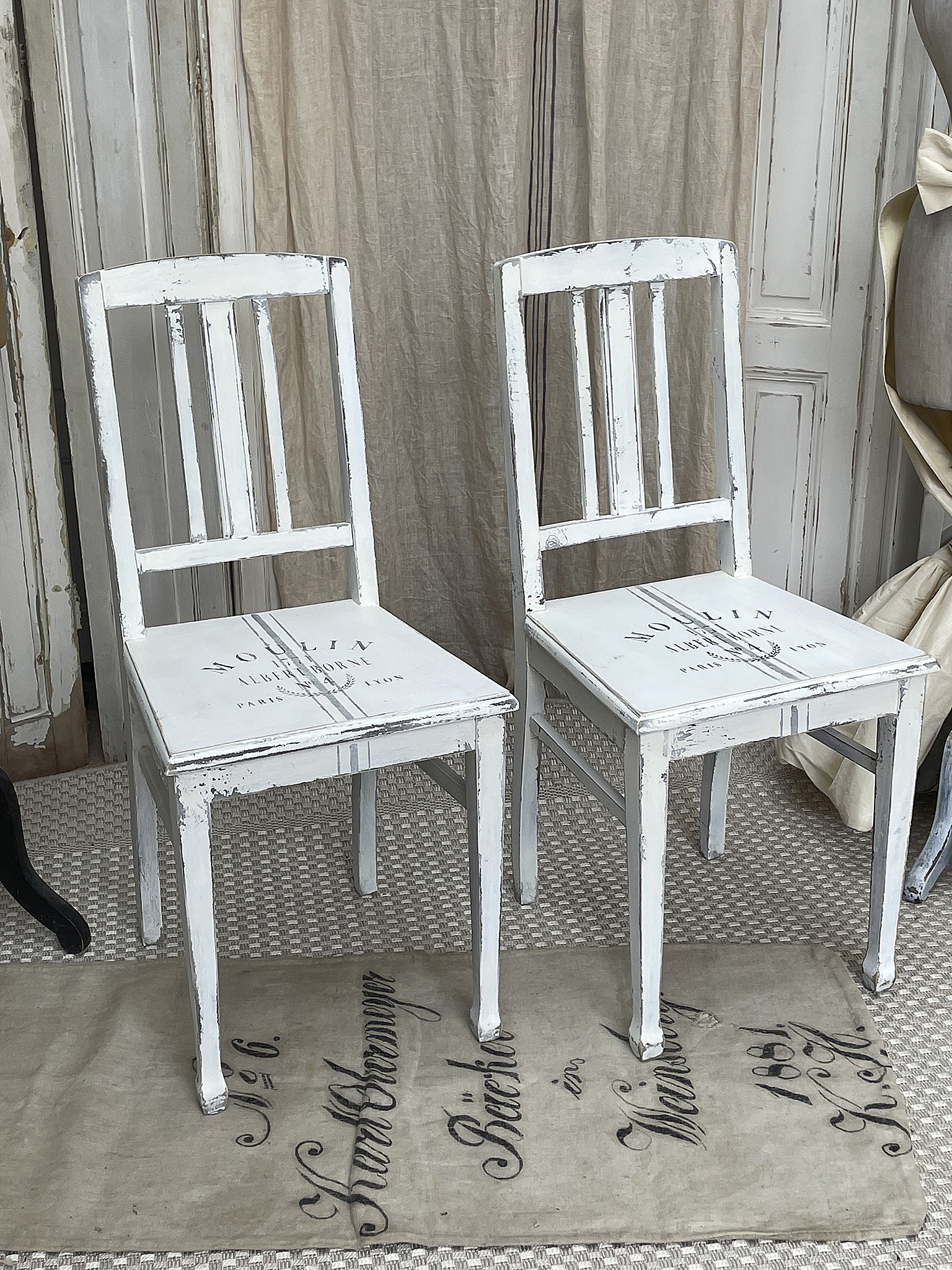 Stilvolle weiße Holzstühle im Vintage-Design Zwei dekorative weiße Holzstühle im Shabby-Chic-Stil mit sichtbaren Gebrauchsspuren.