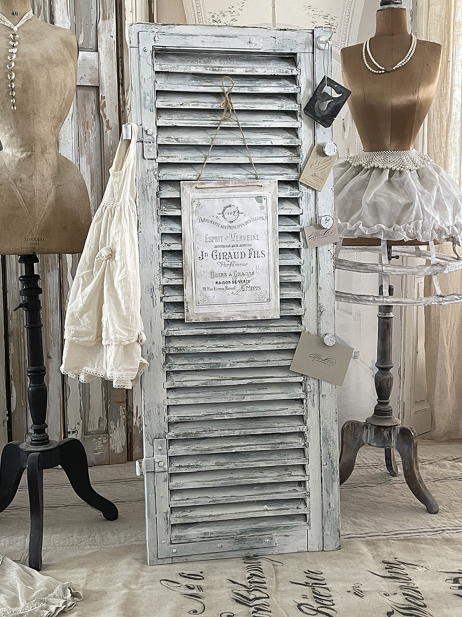 Vintage Shutter mit Dekoration für elegantes Ambiente Dekorativer vintage Fensterladen mit Kleidungsstücken und Schmuck in einem stilvollen Raum