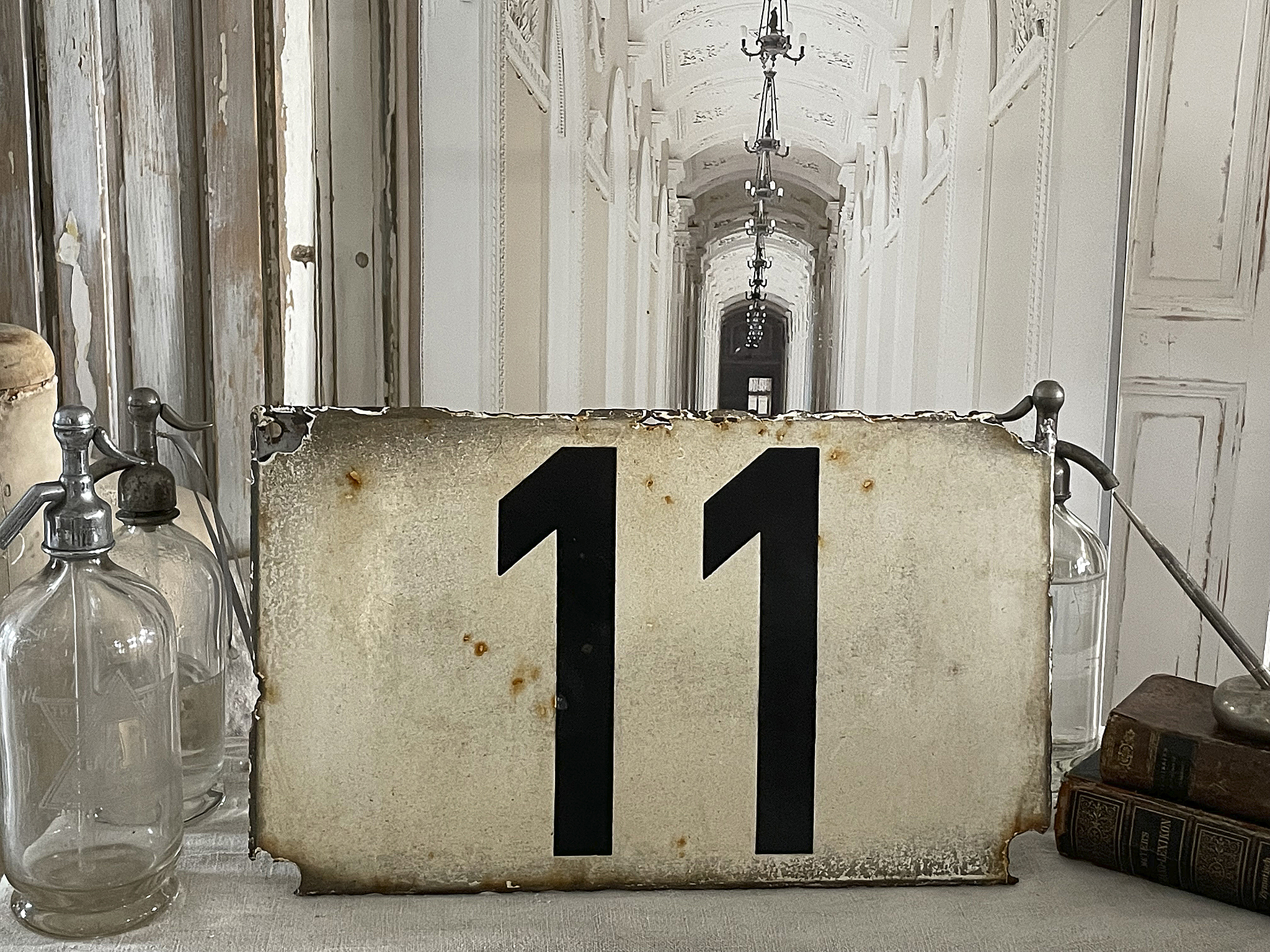 Nummernschild mit der Zahl 11, umgeben von alten Flaschen und Büchern