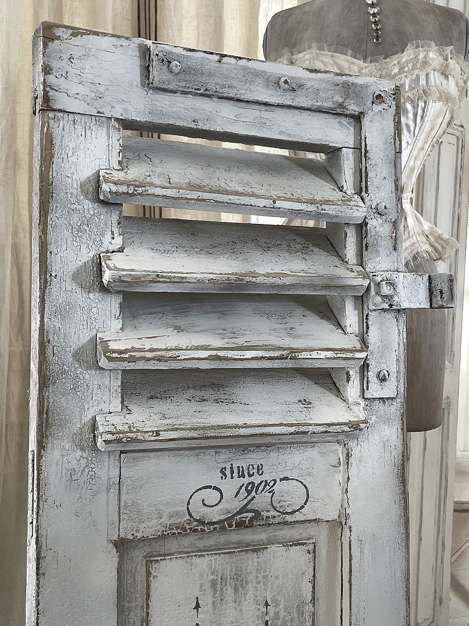Antike Fensterläden in Weiß mit Vintage-Details Detailaufnahme von antiken weißen Fensterläden mit dem Schriftzug 'since 1902'