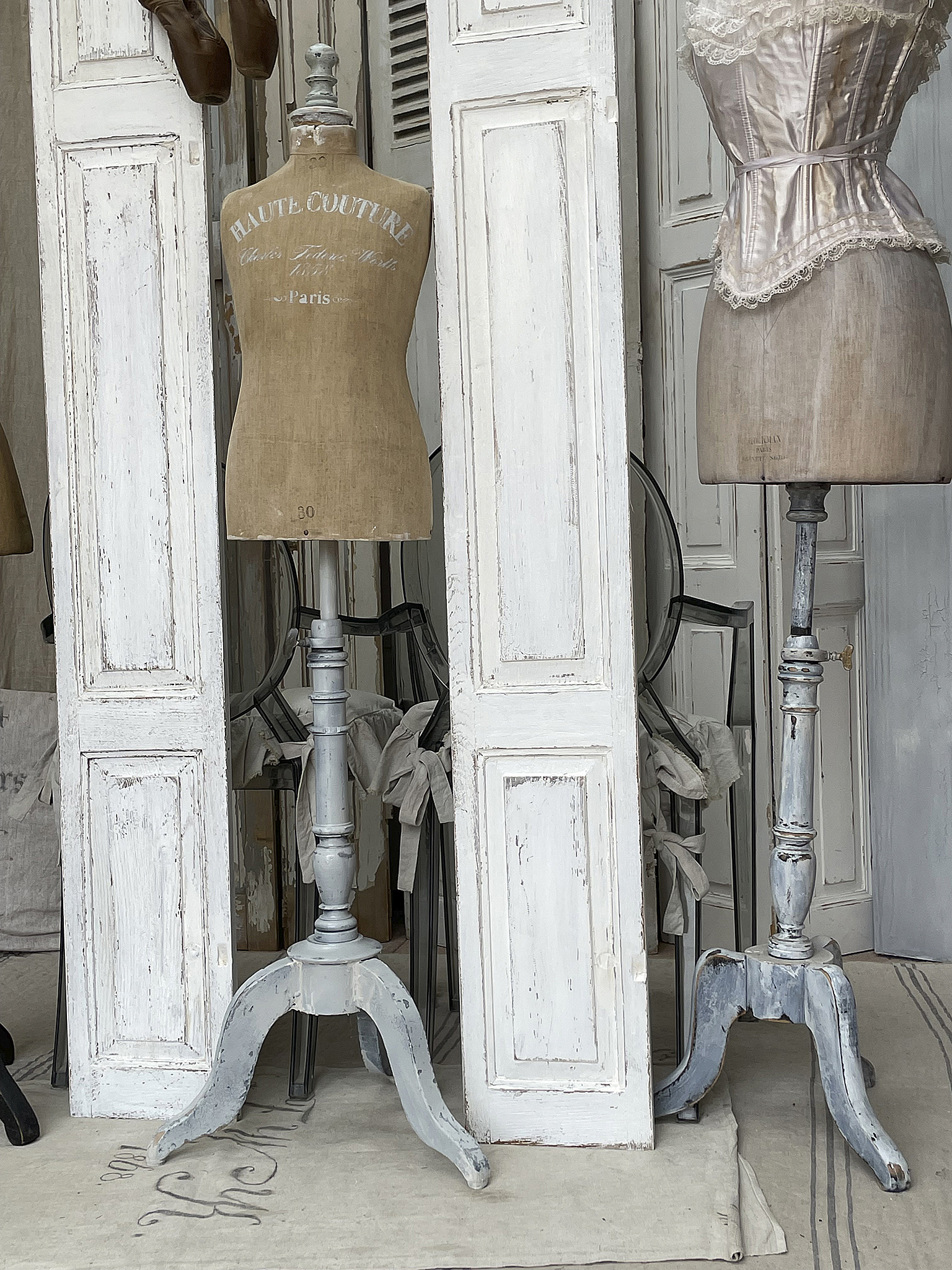Vintage Schneiderpuppen in einem stilvollen Atelier Zwei klassische Schneiderpuppen stehen zwischen weißen Türen in einem eleganten Raum.