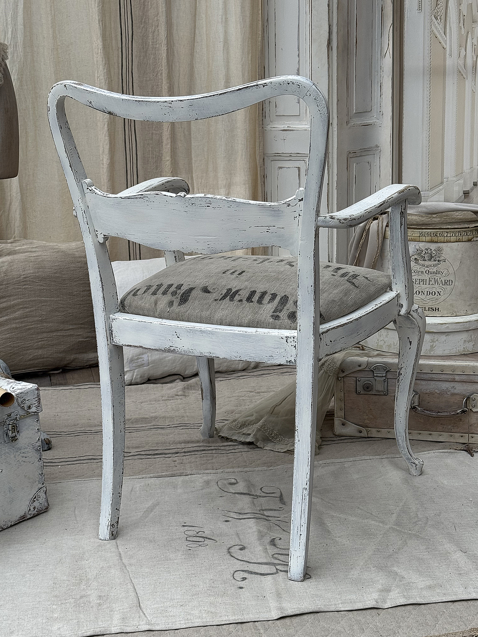 Eleganter weißer Stuhl mit Stoffbezug und vintage Charakter Rückansicht eines eleganten weißen Stuhls mit antikem Flair und gepolsterter Sitzfläche