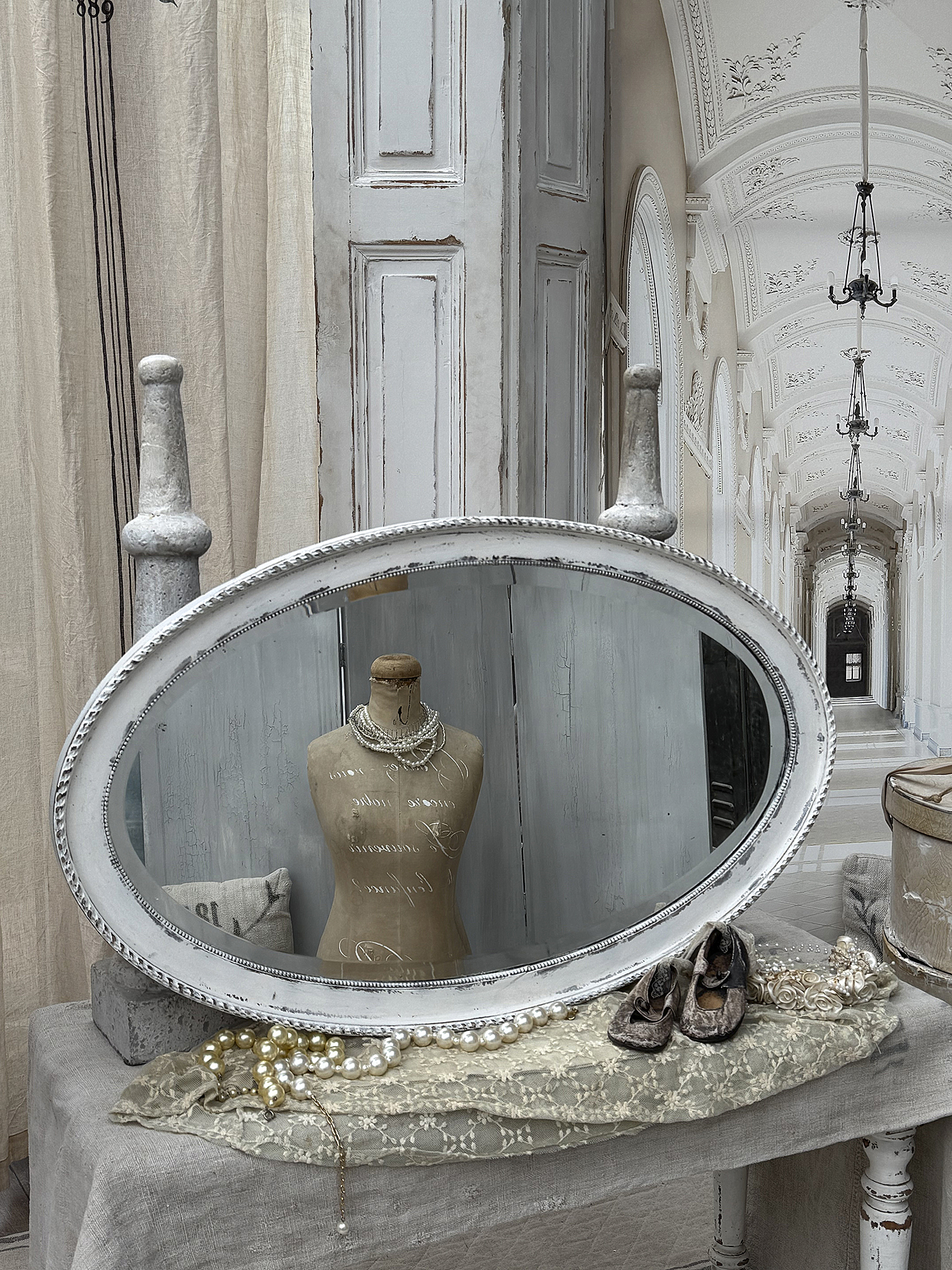 Eleganter Spiegel mit Mannequin und Schmuck auf einem Tisch Ein ovaler Spiegel reflektiert ein Mannequin und Schmuck, umgeben von dekorativen Elementen in einem stilvollen Raum.