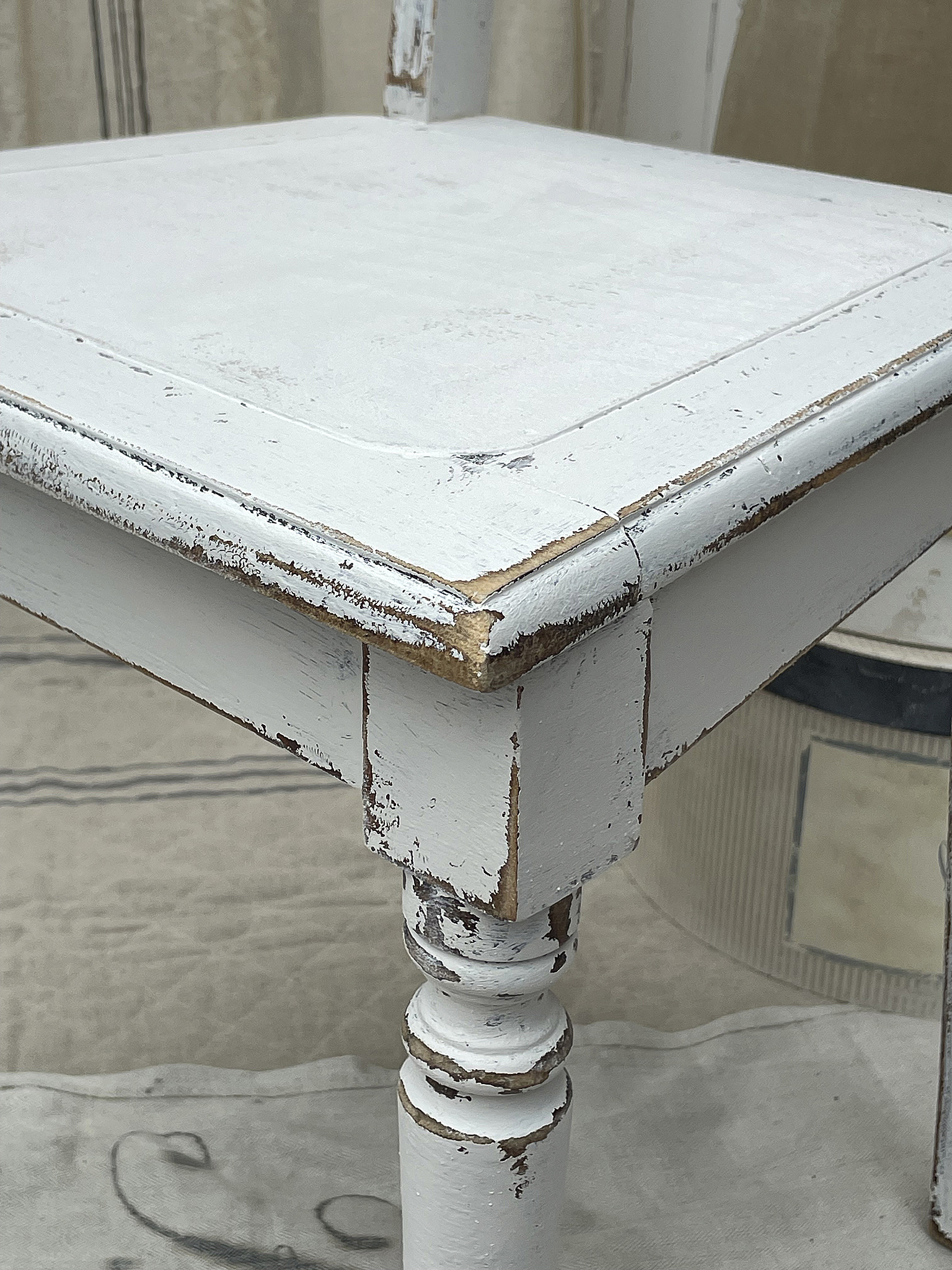 Vintage Holztisch mit weißer Lackierung und verwaschenem Finish Detailaufnahme eines vintage weißen Holztisches mit sichtbaren Gebrauchsspuren und Patina