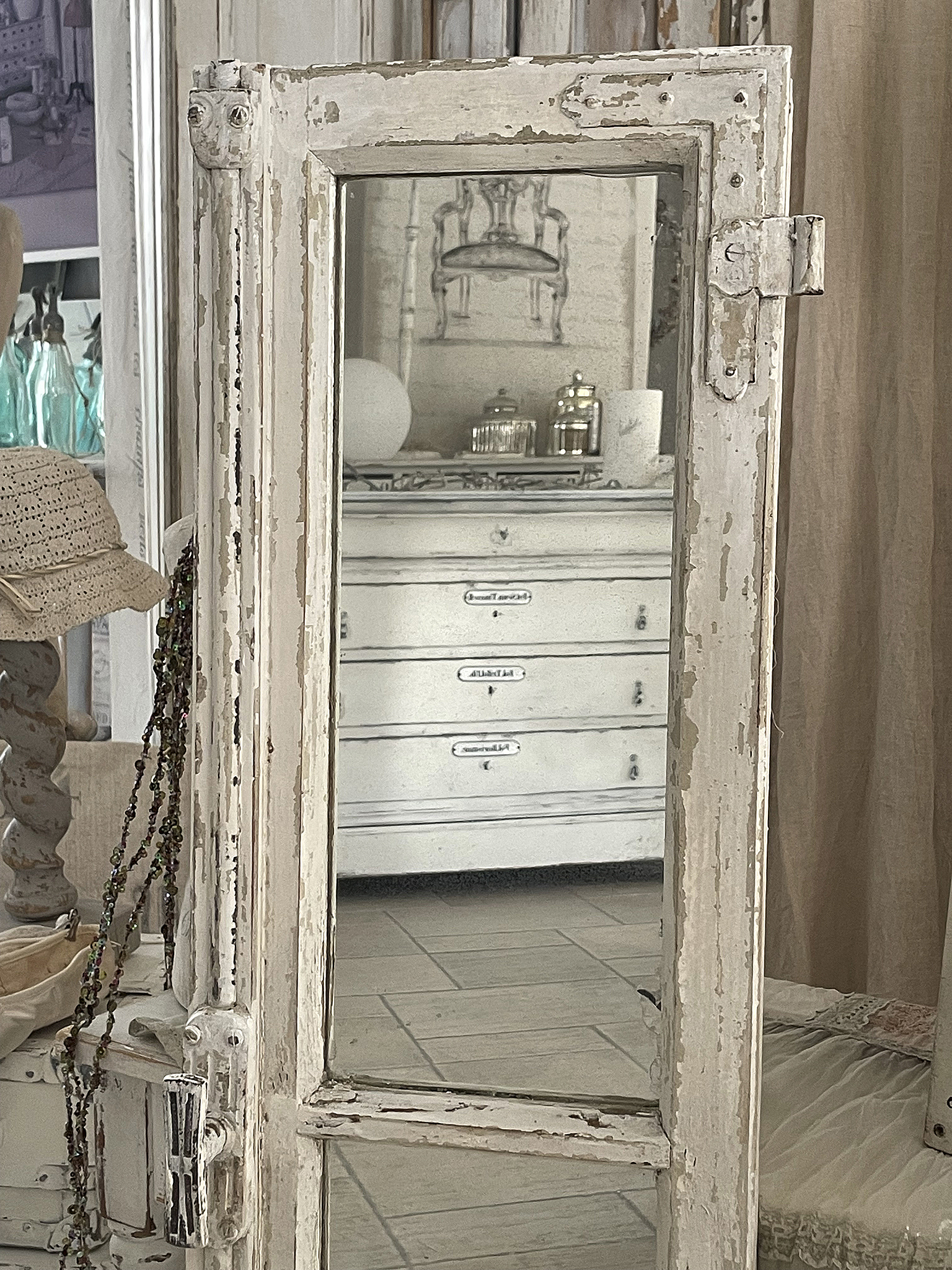 Antiker Spiegel im Shabby Chic Design mit schönem Rahmen Antiker Spiegel mit abgenutztem Rahmen, auf einem Tisch mit weißen Möbeln im Hintergrund