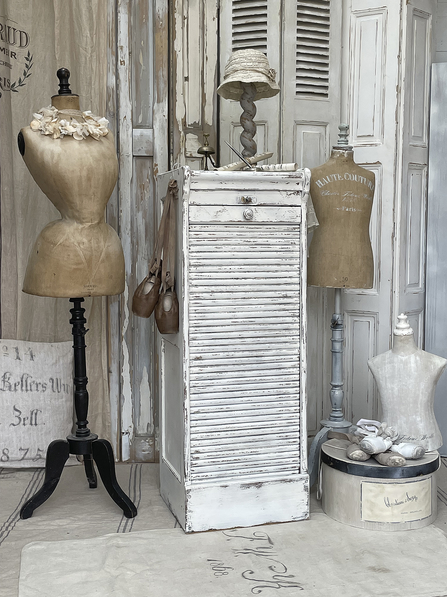 Stilvolles Vintage-Mobiliar für ein charmantes Ambiente Ein nostalgisches Arrangement mit zwei Schmuckpuppen, einem weißen Schrank und einem eleganten Hutständer.