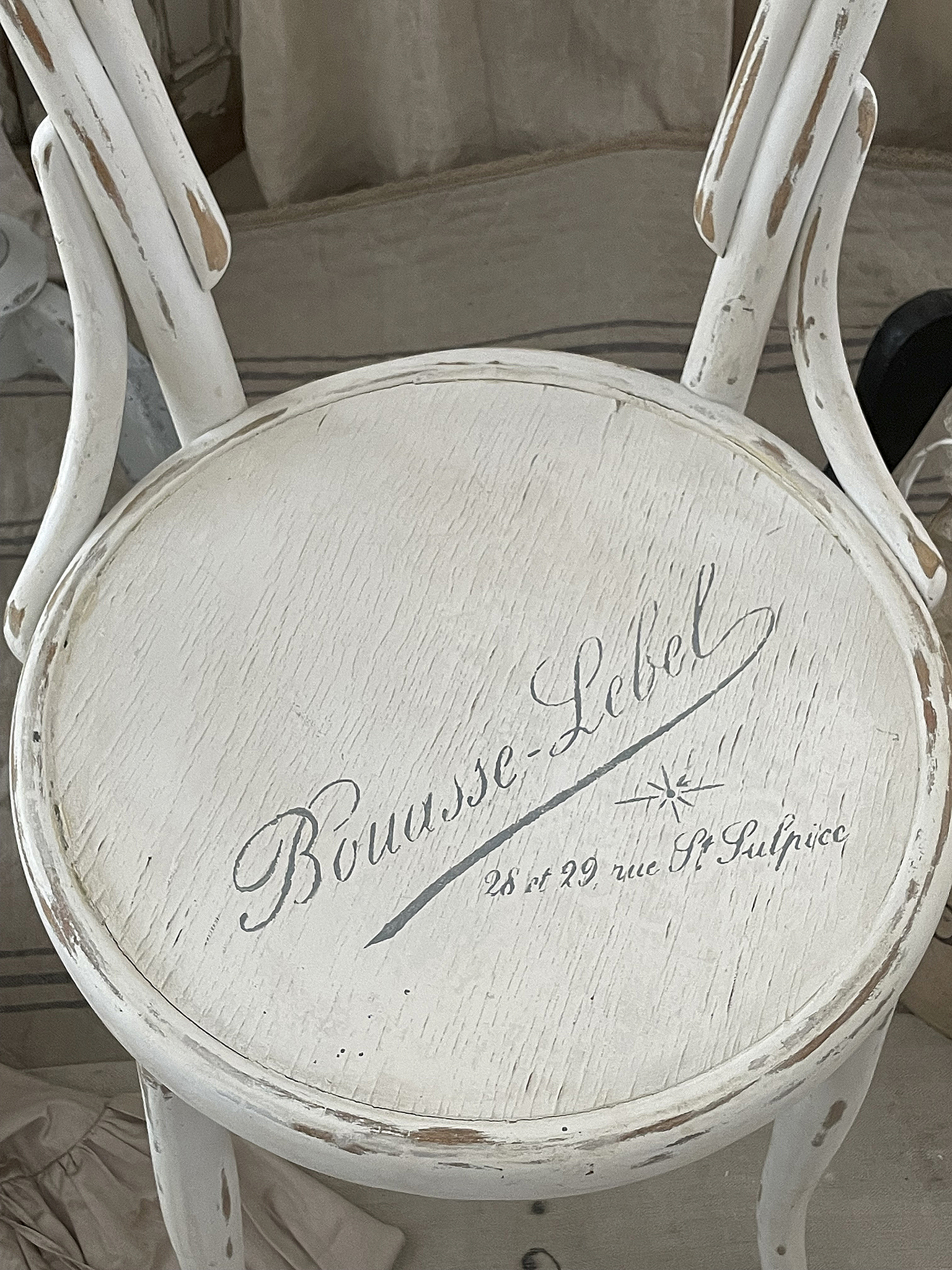 Klassischer, weißer Hocker mit beschrifteter Sitzfläche Dekorativer Hocker mit vintage Schriftzug Bouasse-Lebel, 28 et 29 rue St Sulpice