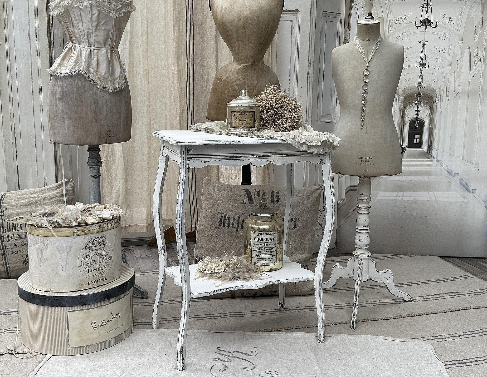 Elegante Vintage-Dekoration mit Kleiderständern und Zubehör Stilvolle Vintage-Dekoration mit Mannequins, nostalgischen Aufbewahrungsboxen und einem Tisch