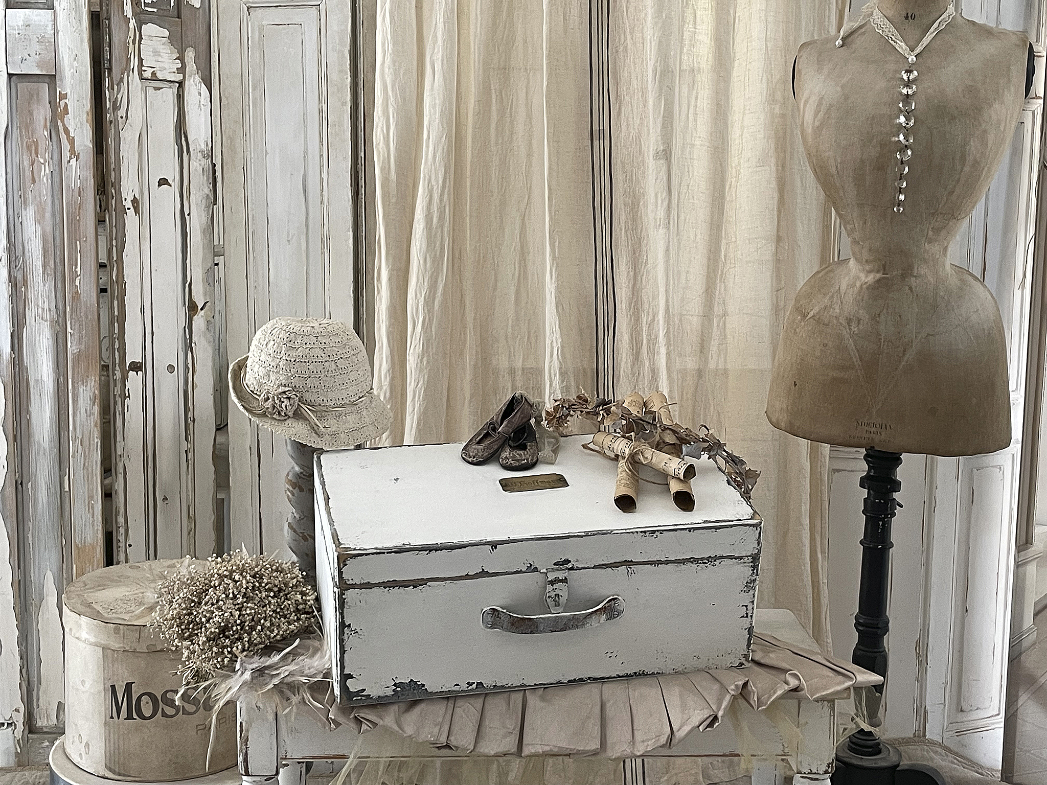 Dekorativer Vintage-Stil mit Box, Hut und Accessoires Ein stilvolles Setup mit einer weißen vintage Box, einem gehäkelten Hut, kleinen Schuhen und einer Stoffpuppe