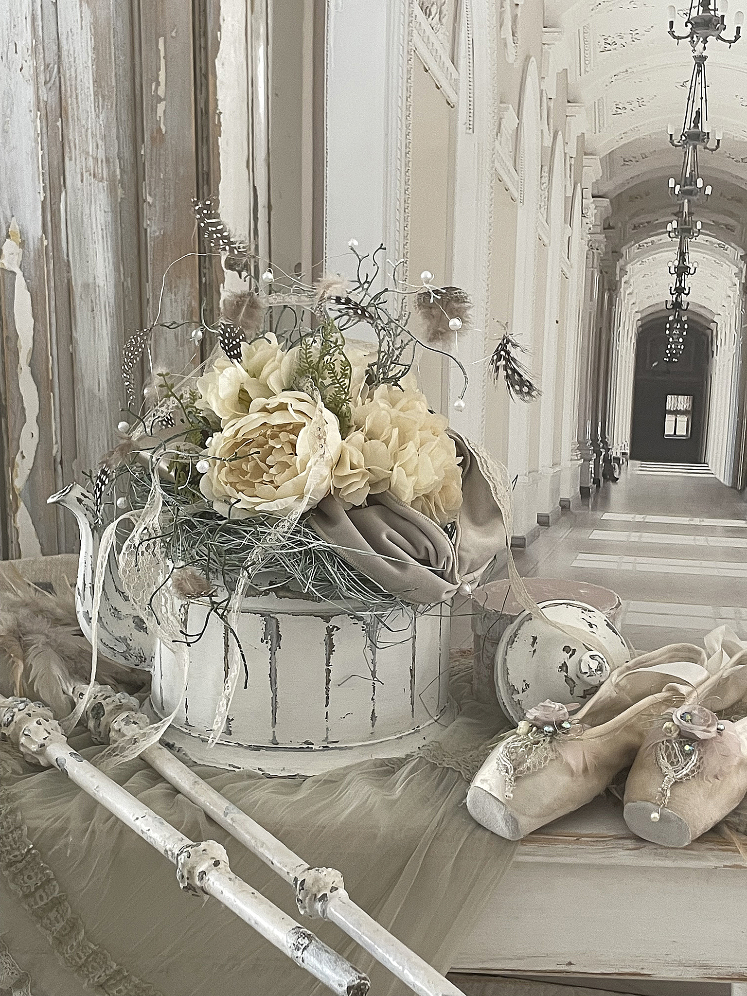 Elegante Deko mit cremefarbenen Blumen und historischen Elementen Dekoratives Arrangement mit Blumen, Stoff und Ballettschuhen in einem schönen Innenraum