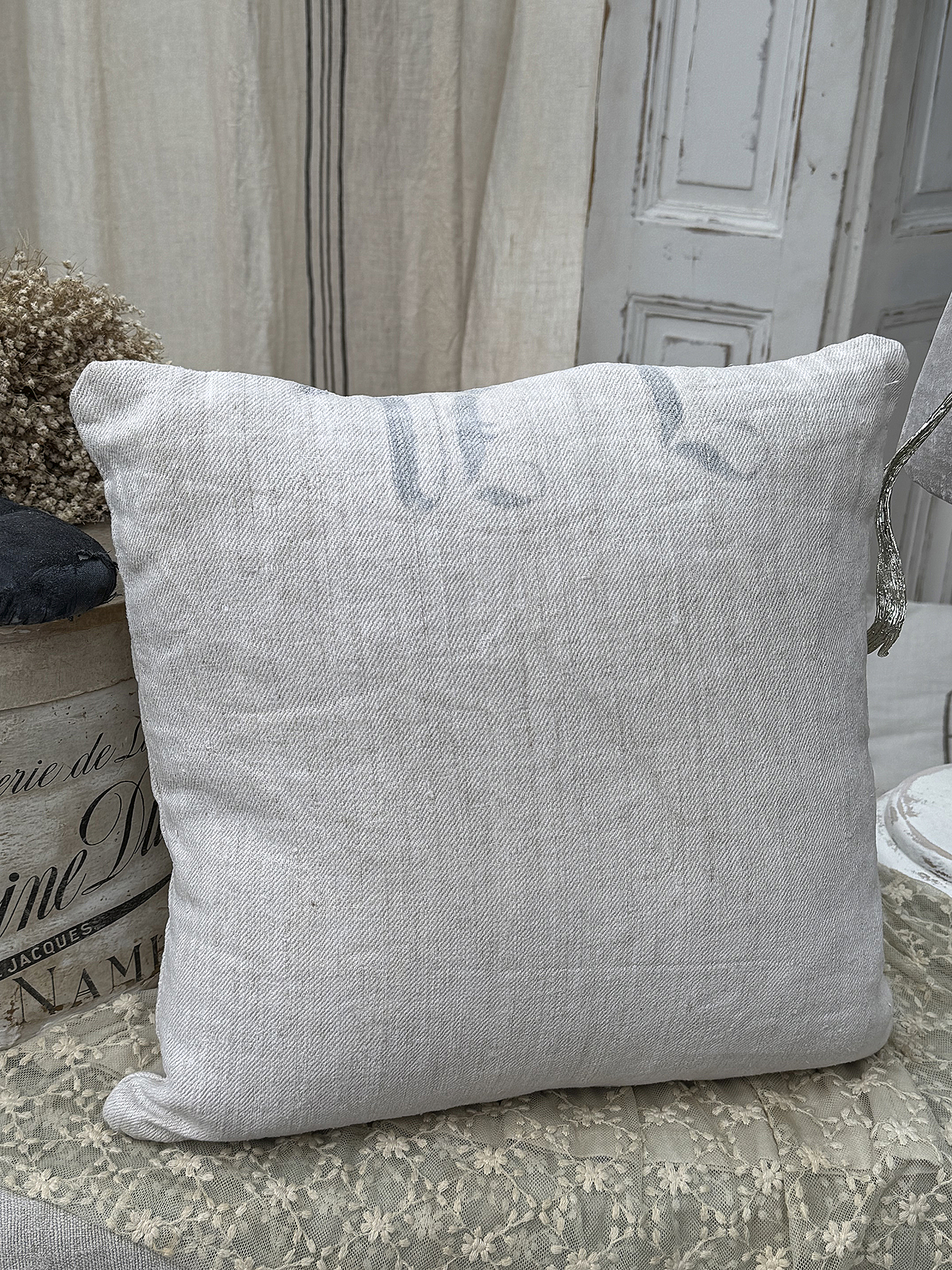 Beige Kissen aus Leinen auf einem Tisch, umgeben von Accessoires.