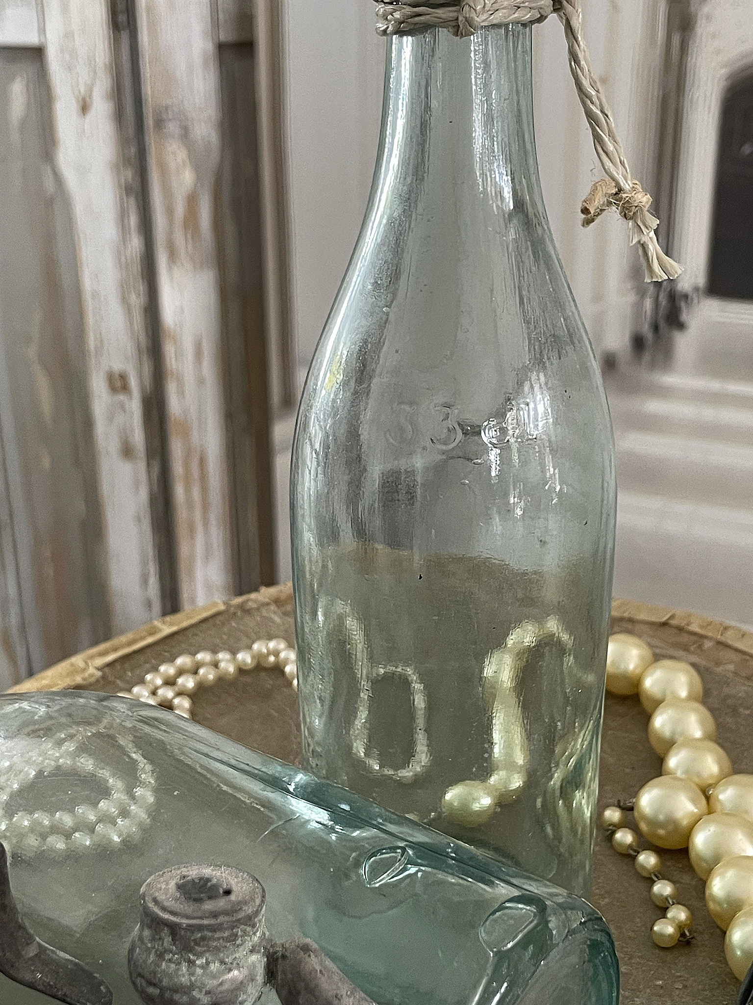 Antike Flasche mit Perlenschmuck auf Holztablett Detailaufnahme einer antiken Flasche und Perlenschmuck auf einem Holztablett