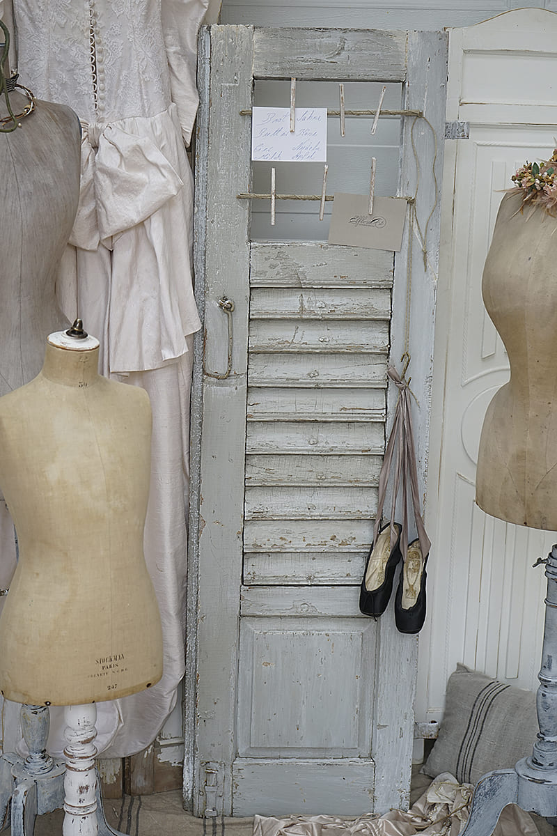 Vintage Tür mit weißen Kleidern und Schuhen in einem nostalgischen Atelier.